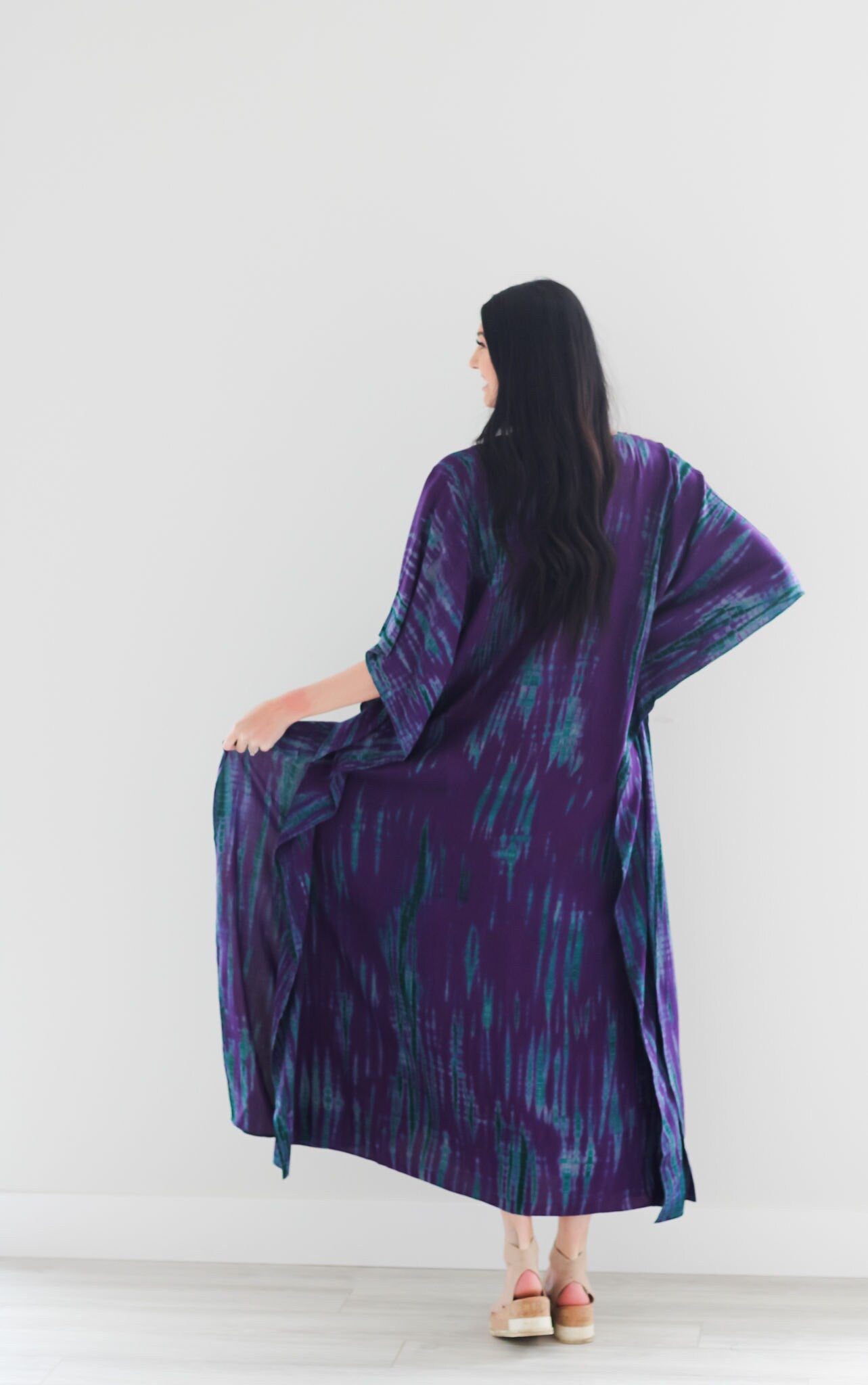 A vibrant purple tie-dyed kaftan dress with pockets, showcasing a v-shaped neck and flowing fabric, perfect for all body types.