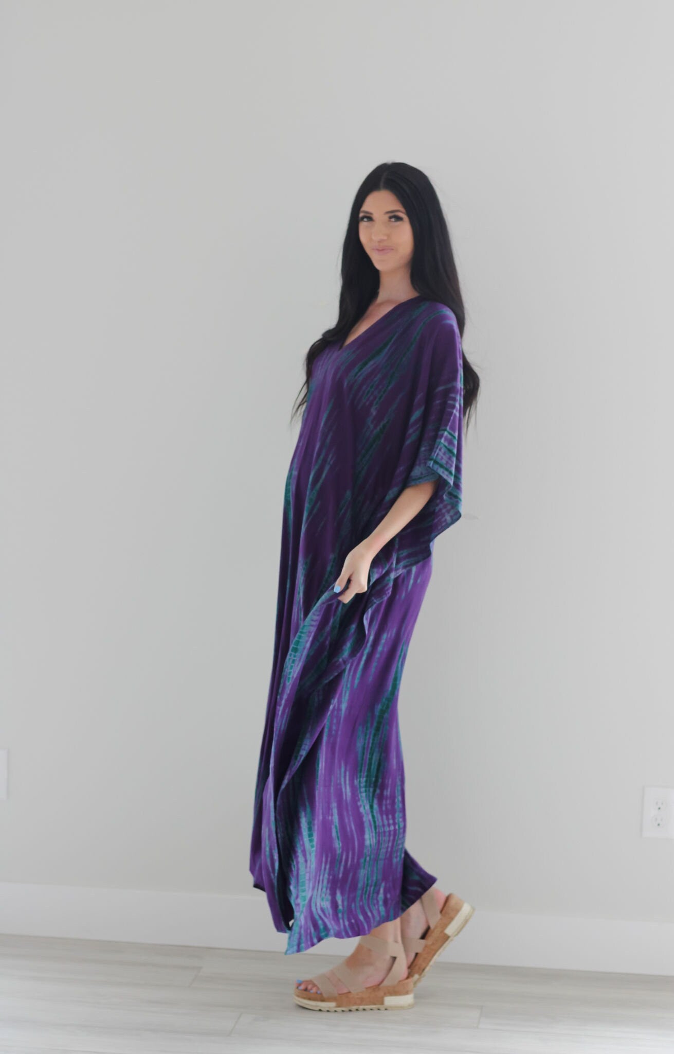 A vibrant purple tie-dyed kaftan dress with pockets, showcasing a v-shaped neck and flowing fabric, perfect for all body types.