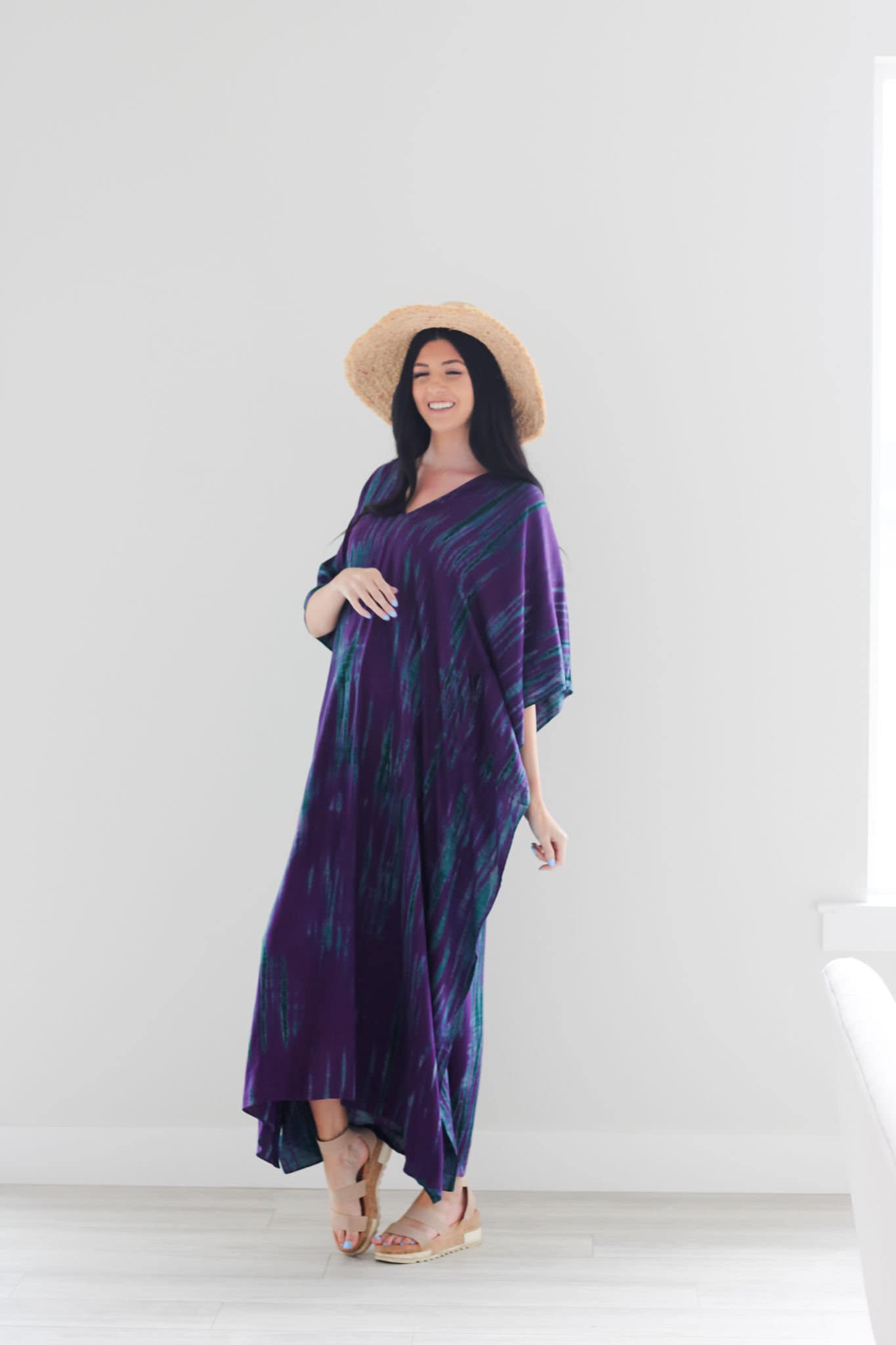 A vibrant purple tie-dyed kaftan dress with pockets, showcasing a v-shaped neck and flowing fabric, perfect for all body types.