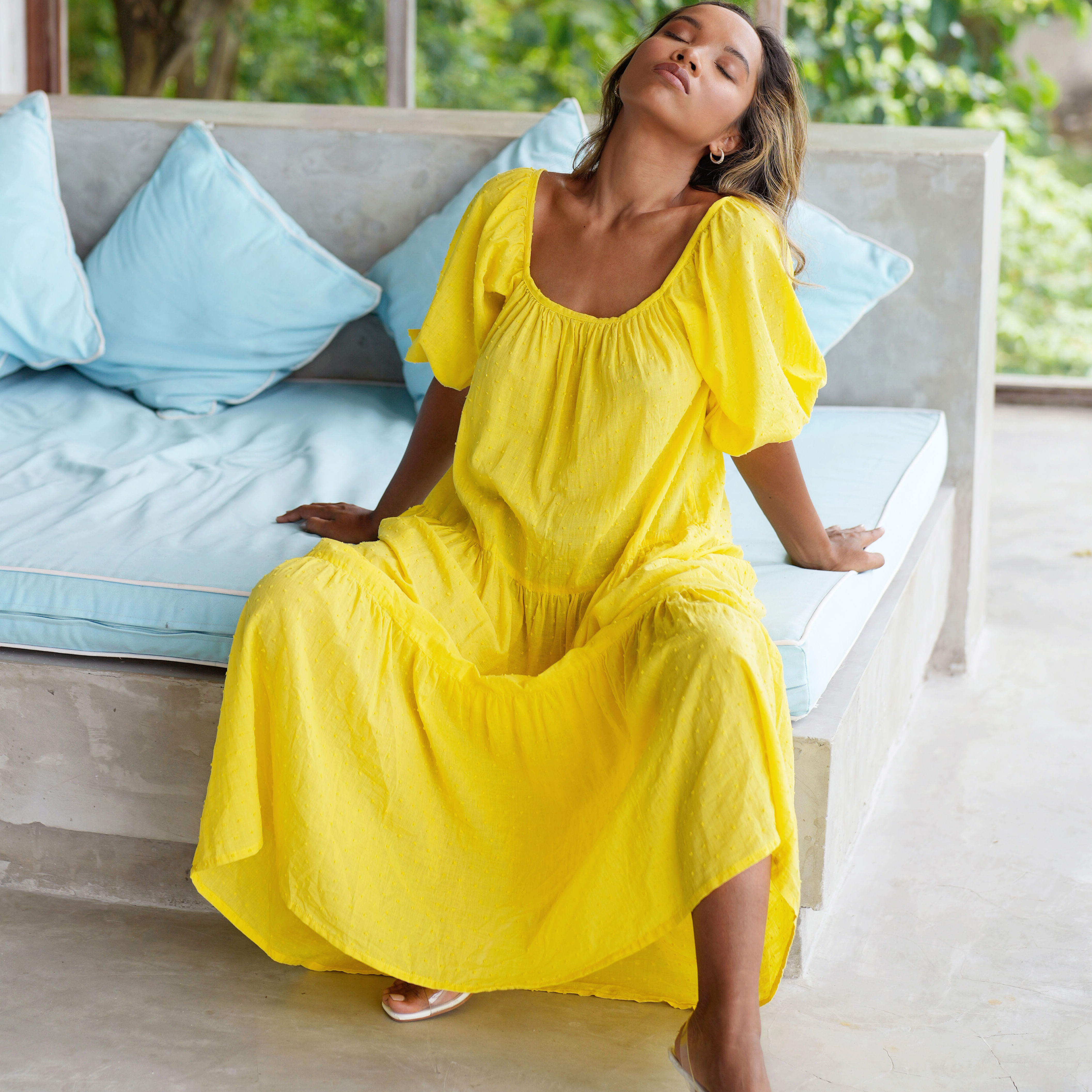 A vibrant sunflower yellow midi dress with dotted pattern, featuring puff sleeves and a tiered skirt, perfect for summer occasions.