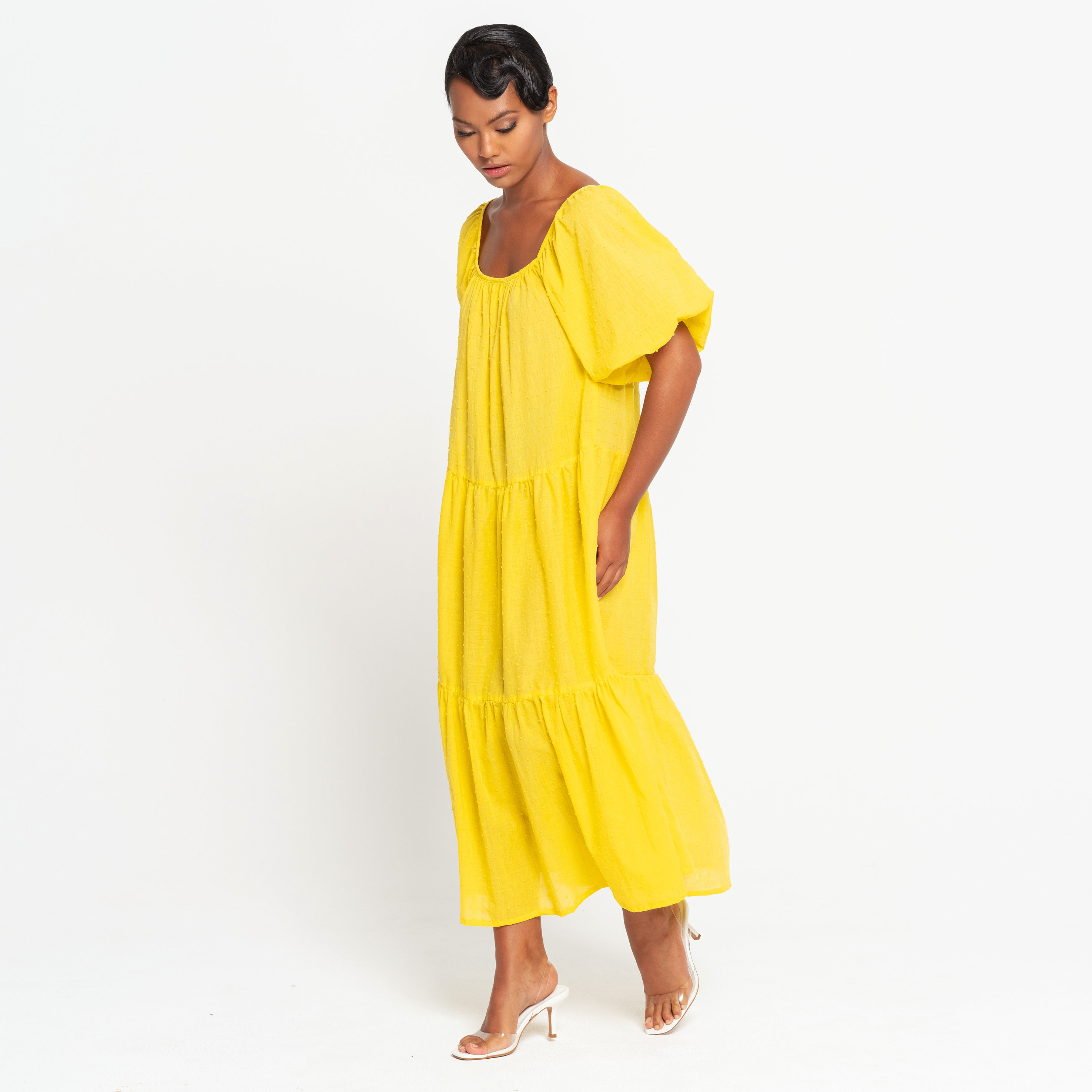 A vibrant sunflower yellow midi dress with dotted pattern, featuring puff sleeves and a tiered skirt, perfect for summer occasions.