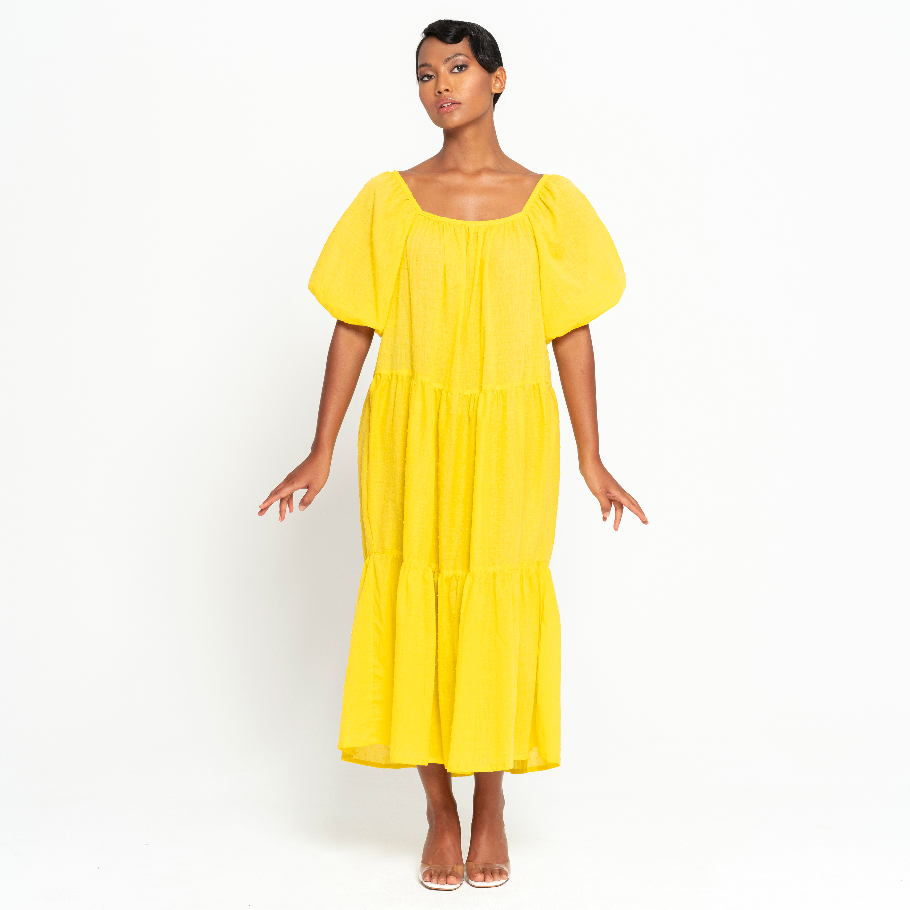 A vibrant sunflower yellow midi dress with dotted pattern, featuring puff sleeves and a tiered skirt, perfect for summer occasions.