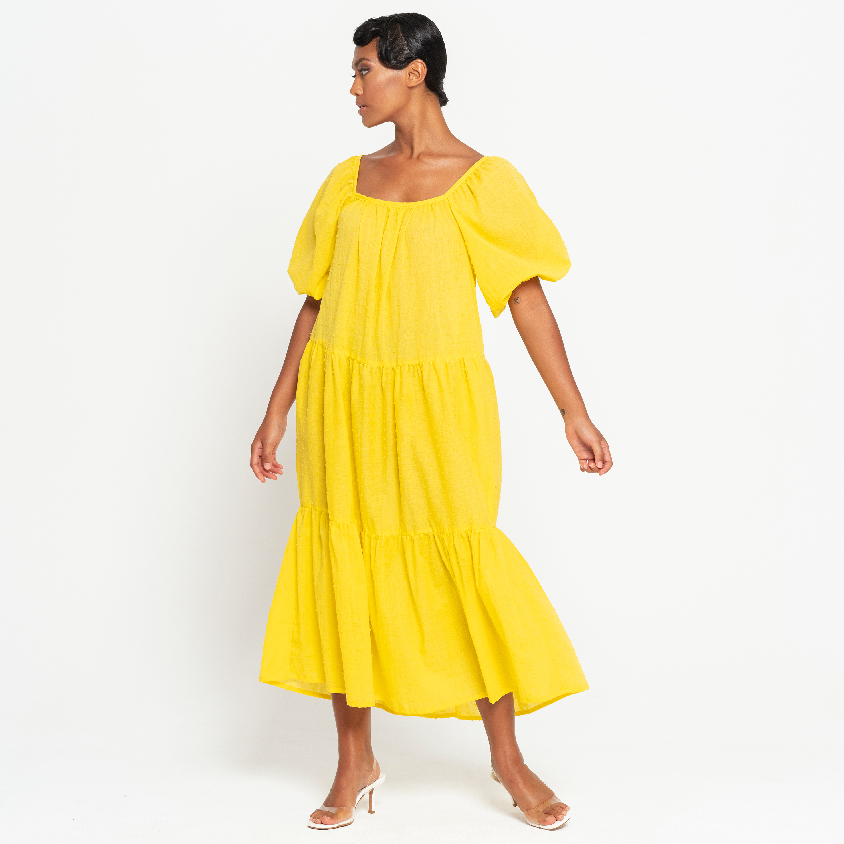 A vibrant sunflower yellow midi dress with dotted pattern, featuring puff sleeves and a tiered skirt, perfect for summer occasions.