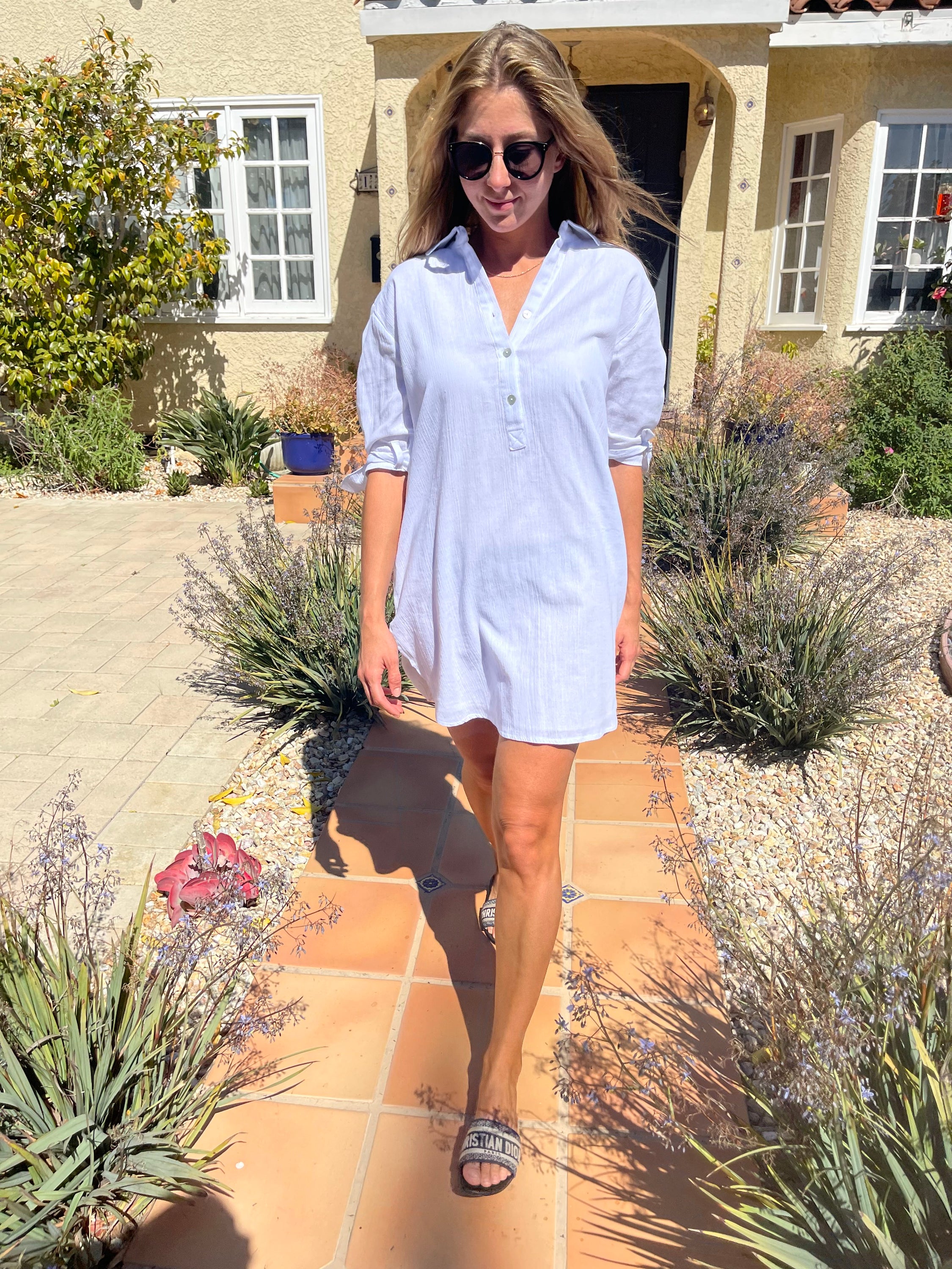 A stylish white mini dress made of lightweight cotton, featuring adjustable tie sleeves, perfect for summer outings.