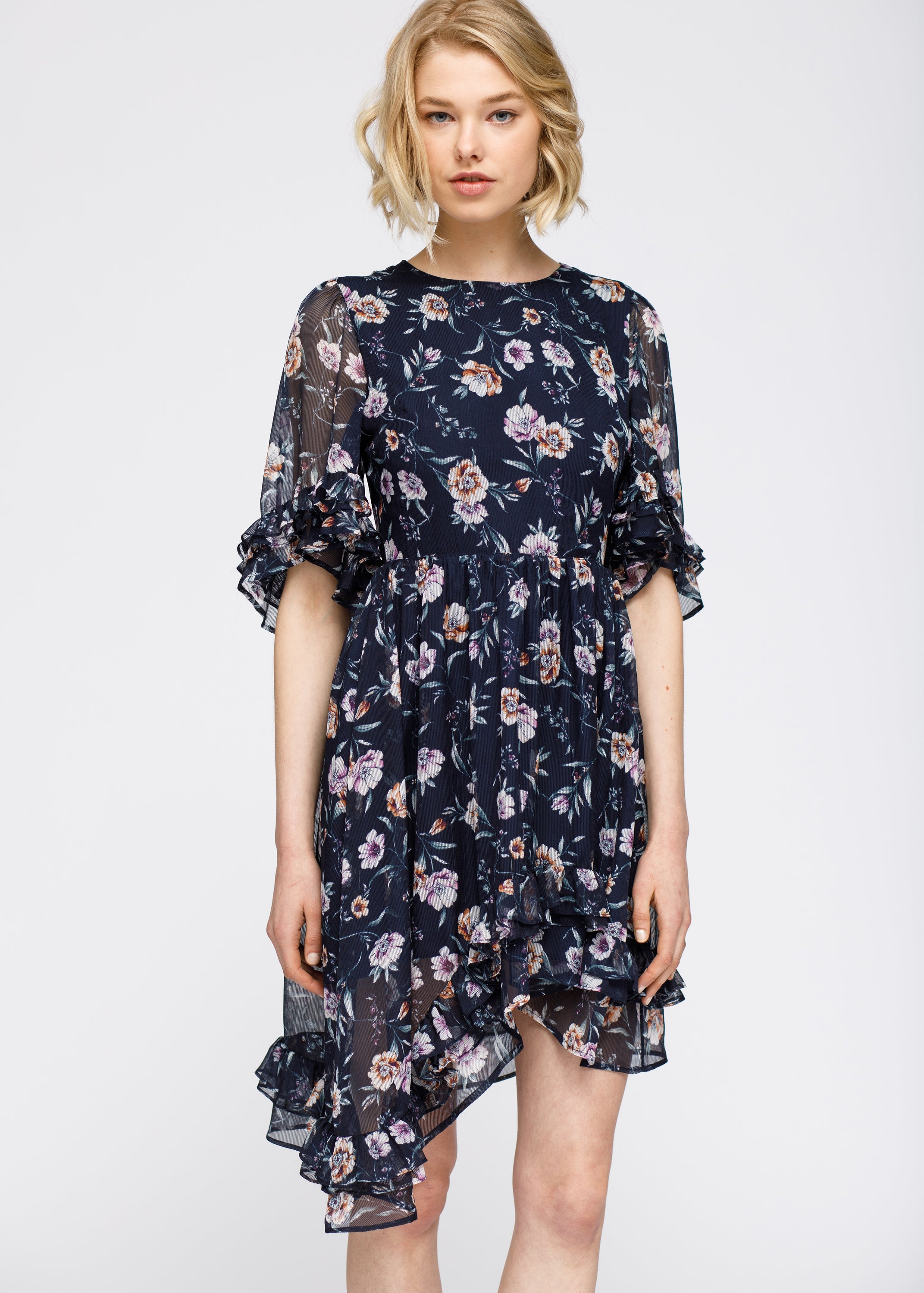 A stylish Wax Flower Asymmetrical Hi-Lo Dress featuring a sheer floral print, ruffle hem, and open back design.