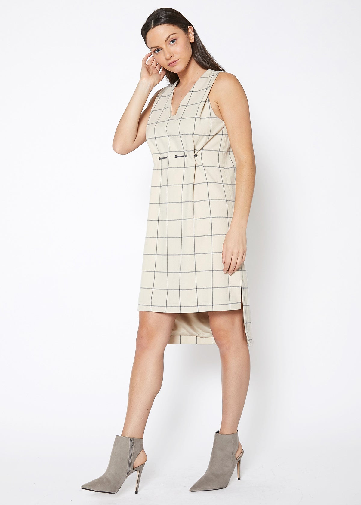 A stylish women's sleeveless dress featuring a high-low hemline and a window pane plaid pattern, perfect for professional and casual occasions.