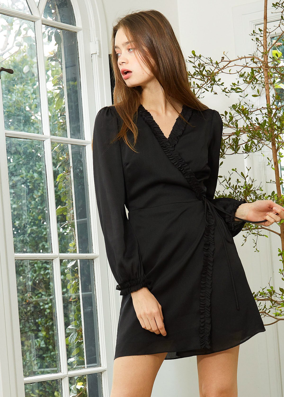 Women's black wrap dress with ruffle trim and long sleeves, showcasing a stylish and elegant design.