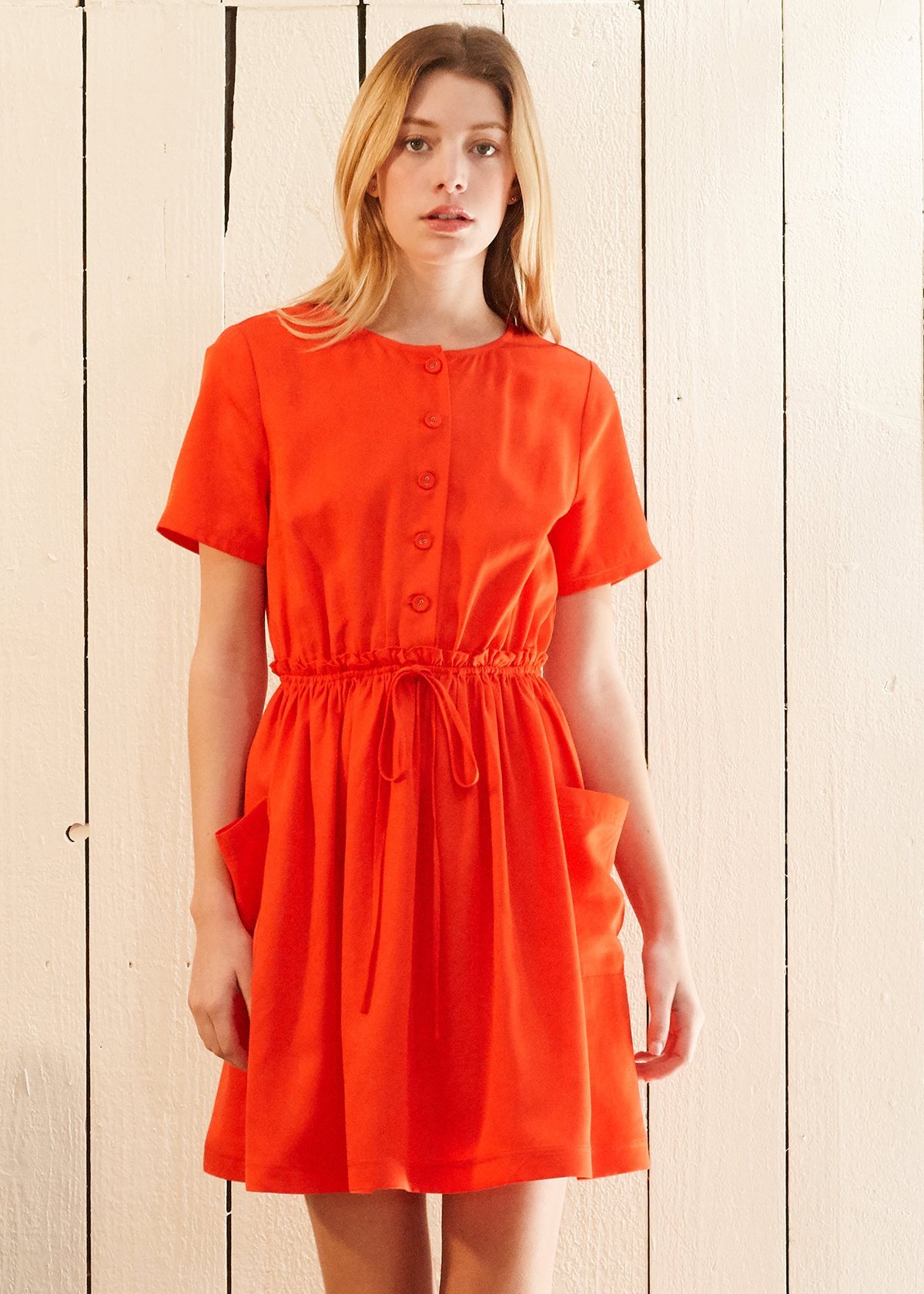 Women's Short Sleeve Utility Dress in vibrant Poppy color, featuring two side pockets and an elastic waist for a comfortable fit.