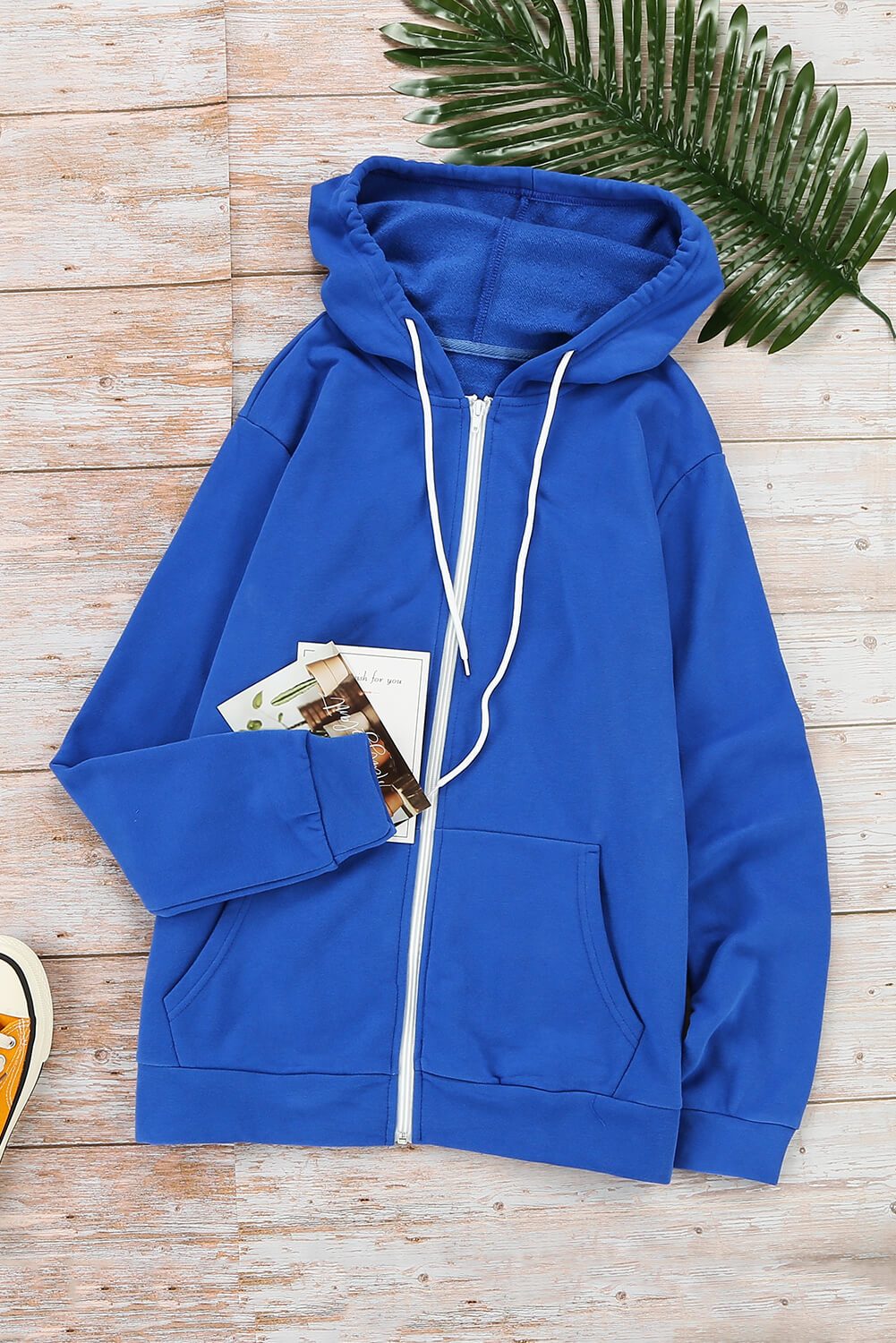 Casual blue zip-up hoodie jacket with white metallic zipper and drawcords, showcasing a stylish and comfortable design for various occasions.