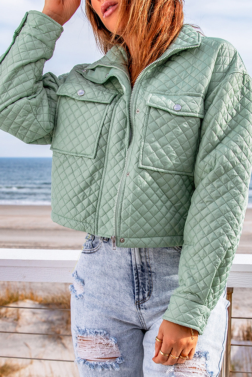 A stylish green quilted cropped jacket with a zip-up front and chic pockets, perfect for winter fashion.