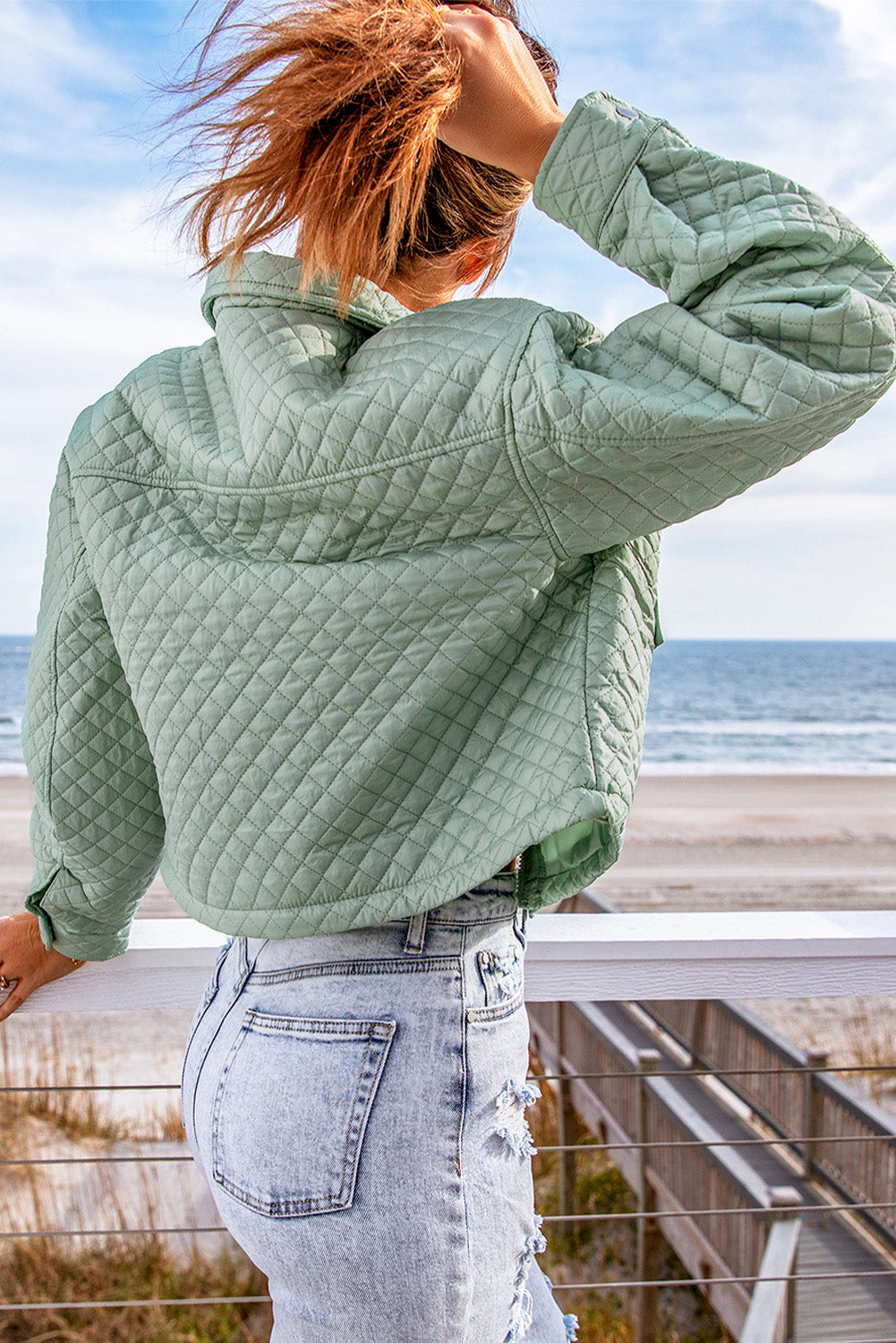 A stylish green quilted cropped jacket with a zip-up front and chic pockets, perfect for winter fashion.