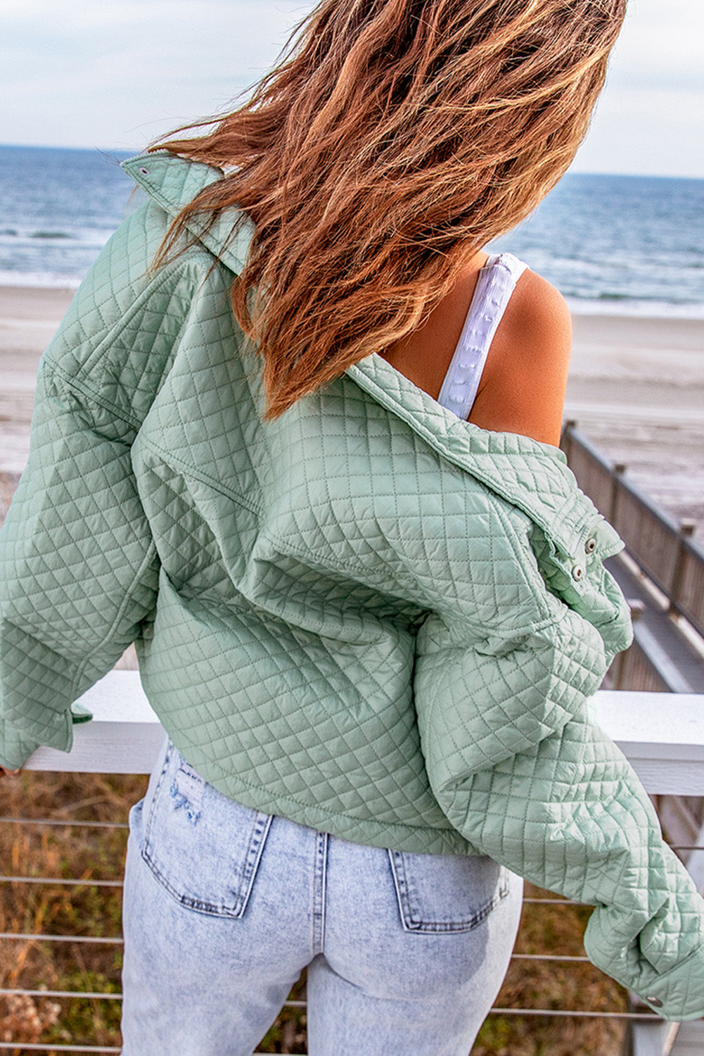 A stylish green quilted cropped jacket with a zip-up front and chic pockets, perfect for winter fashion.