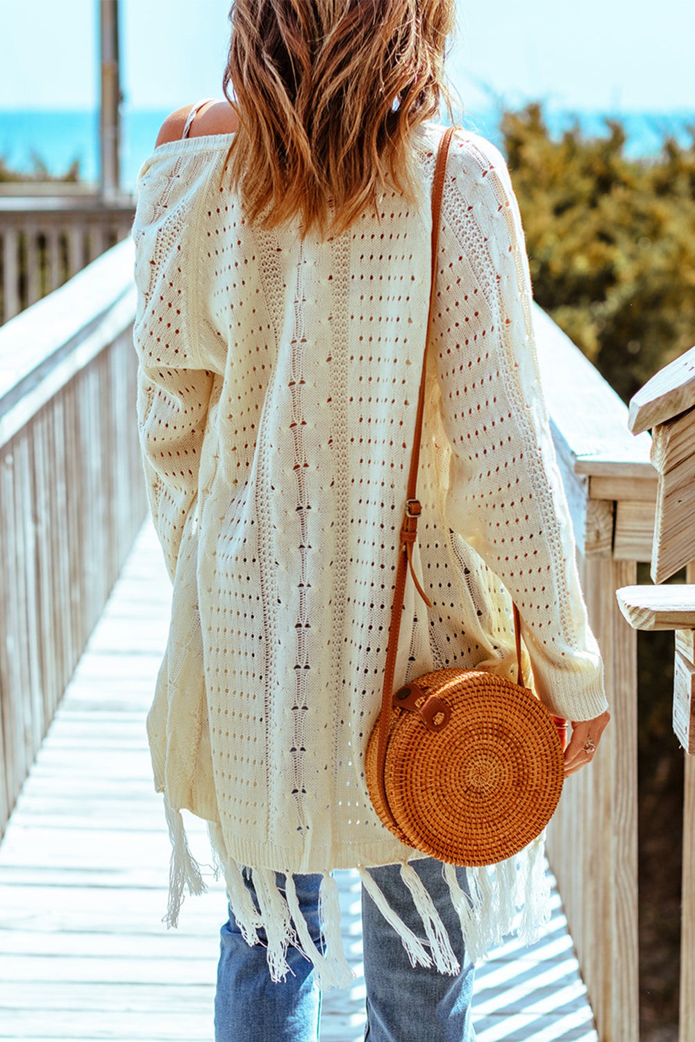 A stylish beige Tasseled Cable Knit Cardigan featuring a hollow design, open front, and flowy fringe, perfect for winter layering.