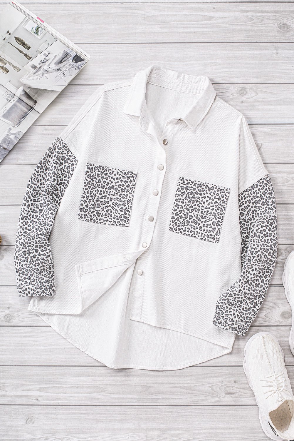 White denim shirt jacket with leopard print sleeves, featuring front snap closures and pockets.