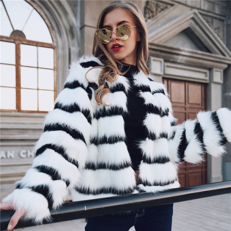 Elegant women's winter coat featuring black and white stripes made of soft faux fur, designed for warmth and style.