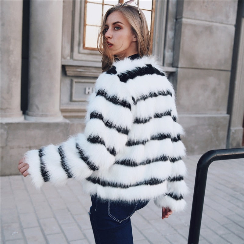 Elegant women's winter coat featuring black and white stripes made of soft faux fur, designed for warmth and style.