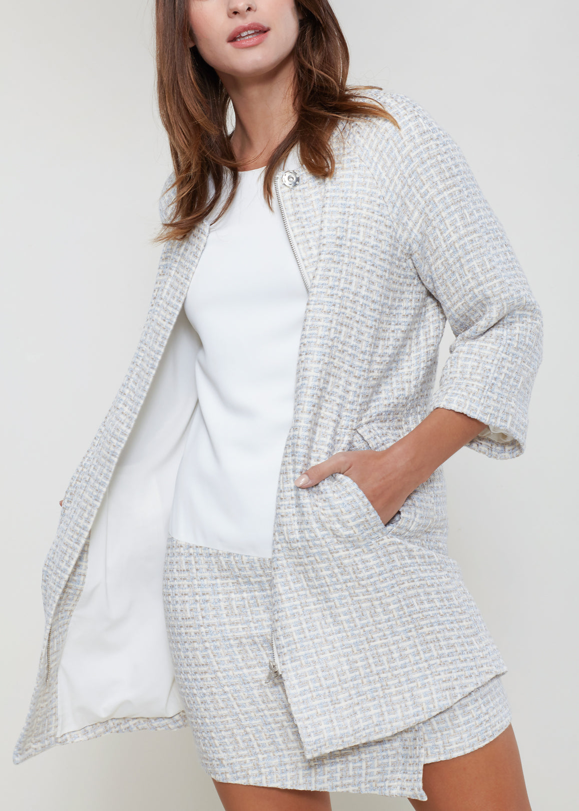 Women's longline tweed jacket in powdered blue with 3/4 sleeves and hidden zip closure, featuring functional pockets.