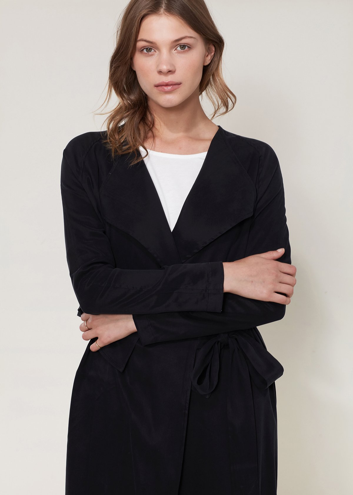 Women's black wrap trench coat featuring a drape collar and side pockets, elegantly tied at the waist.