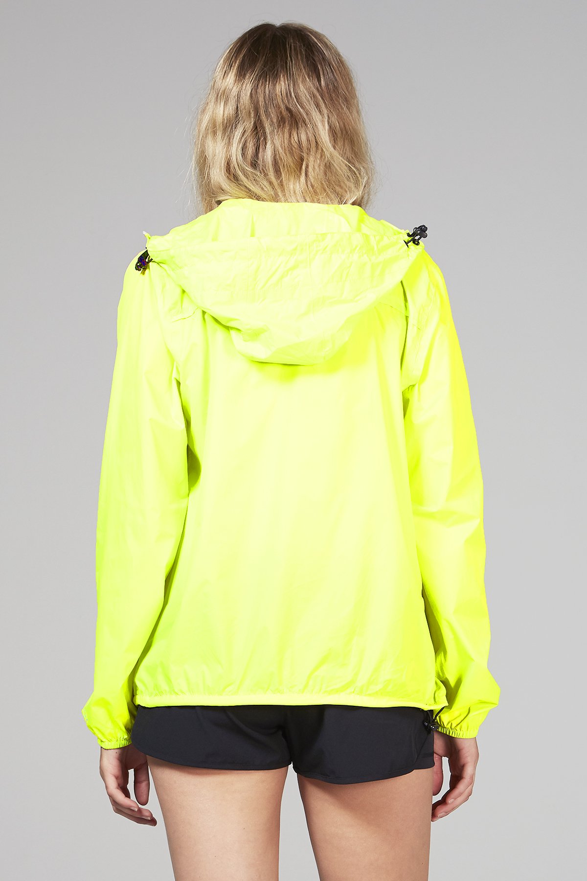 A vibrant yellow fluo full zip packable rain jacket, showcasing its waterproof material and compact design, perfect for outdoor activities.