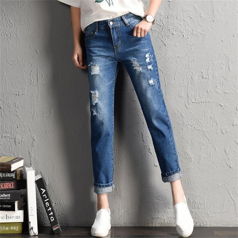 A pair of stylish mid-waist boyfriend jeans featuring big ripped holes, made from a soft cotton-polyester blend, perfect for casual wear.