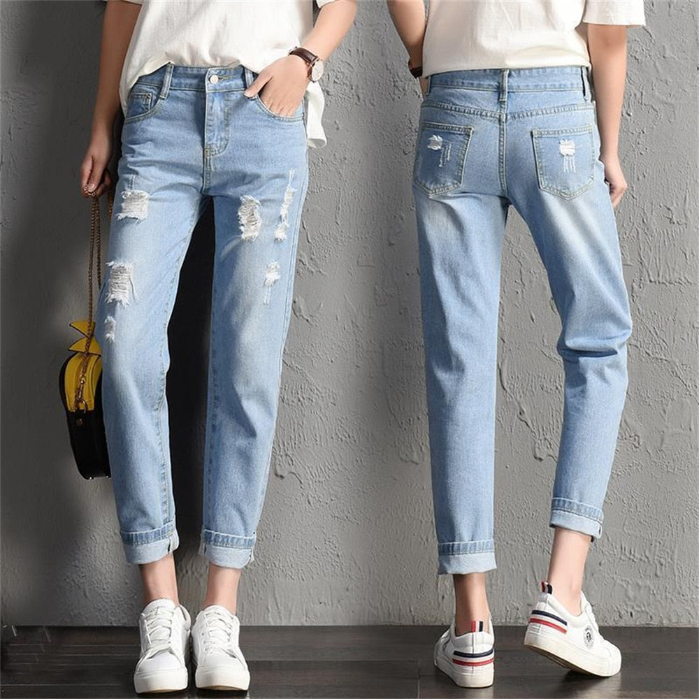 A pair of stylish mid-waist boyfriend jeans featuring big ripped holes, made from a soft cotton-polyester blend, perfect for casual wear.