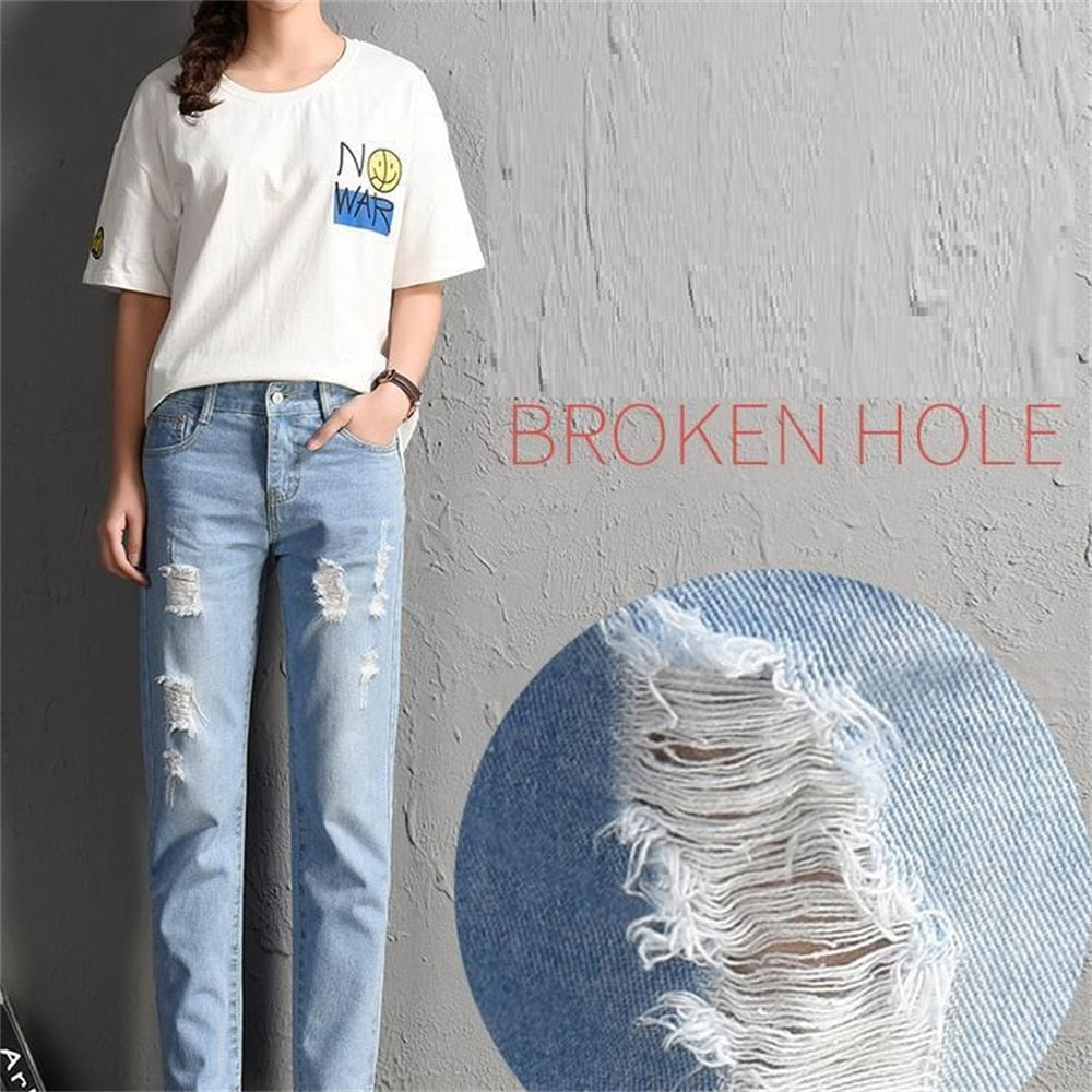 A pair of stylish mid-waist boyfriend jeans featuring big ripped holes, made from a soft cotton-polyester blend, perfect for casual wear.