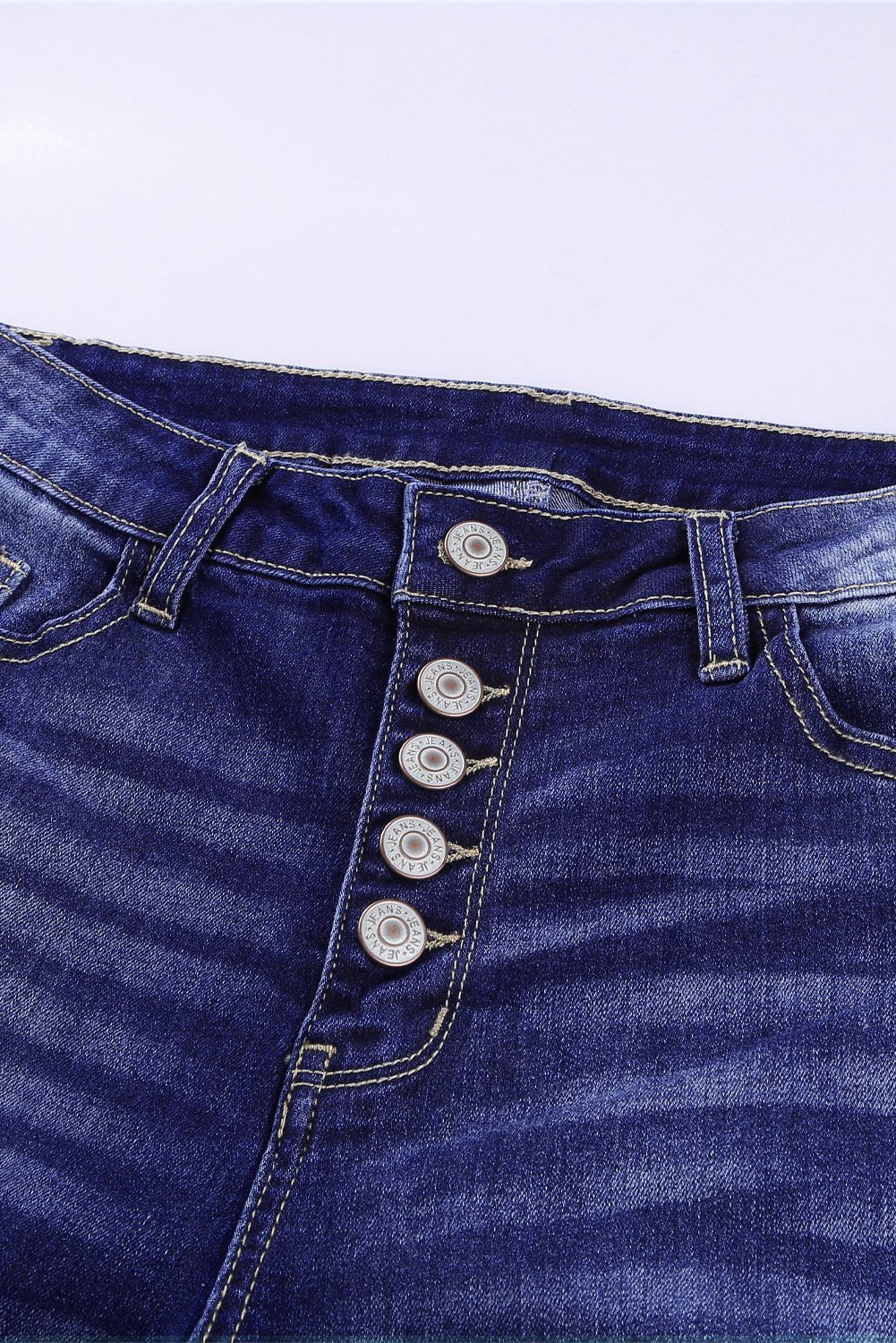 High Rise Button Front Frayed Ankle Skinny Jeans in medium wash with distressed details and raw edges, showcasing front button closures and five pockets.