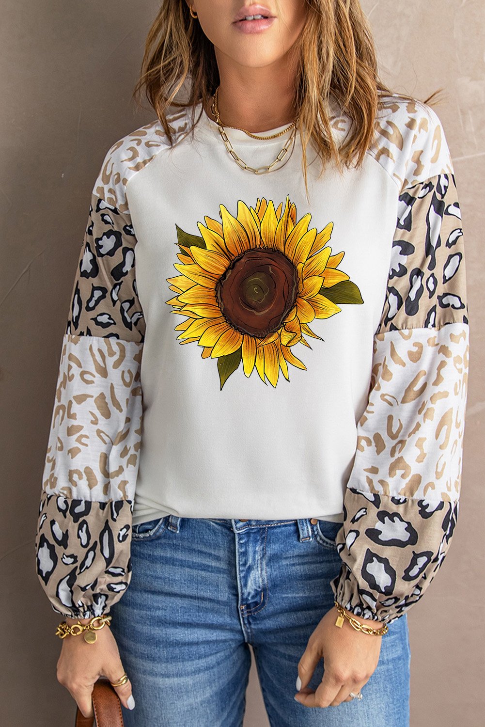 A stylish beige long sleeve top featuring sunflower and leopard prints, designed with bubble sleeves and a loose pullover silhouette.