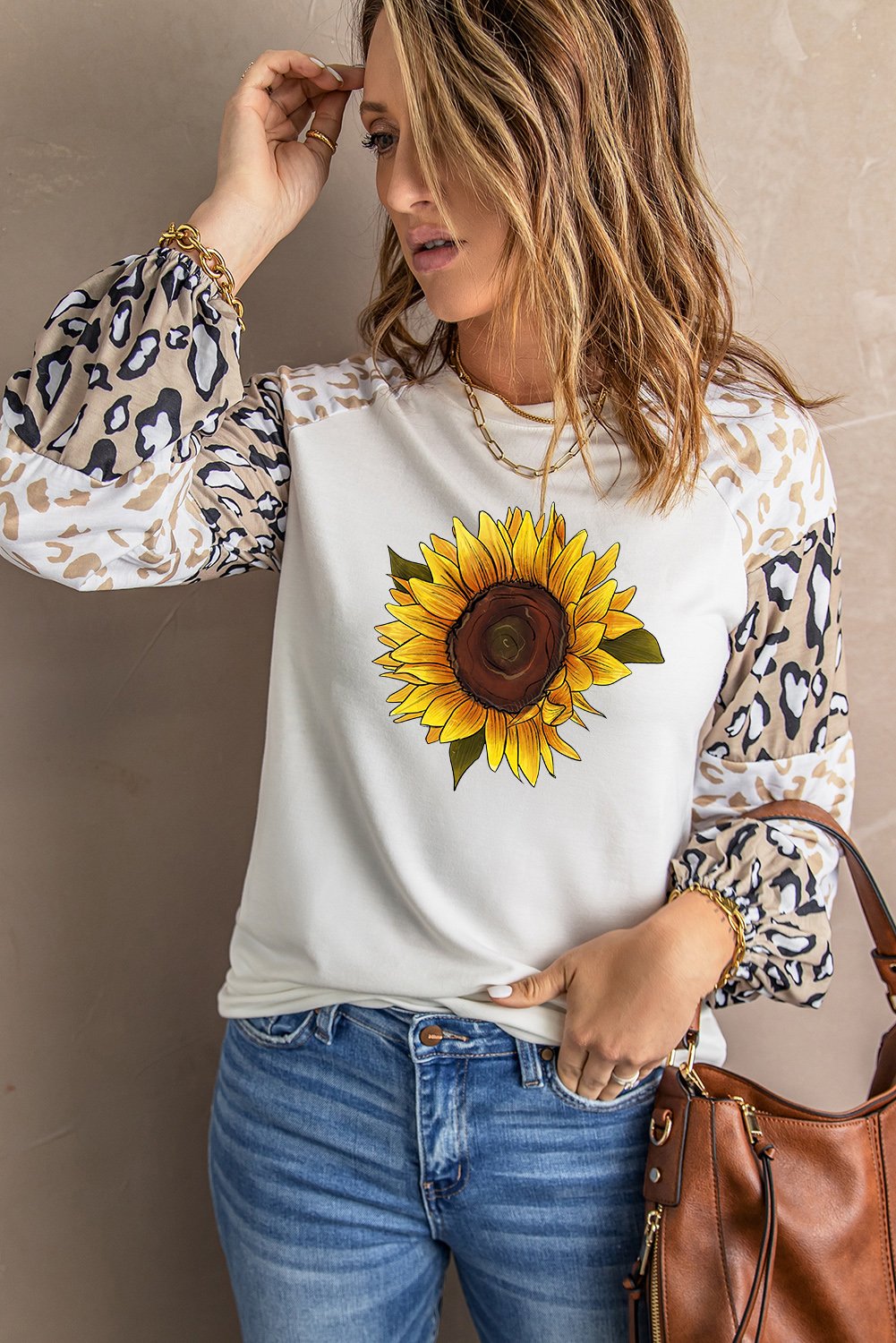 A stylish beige long sleeve top featuring sunflower and leopard prints, designed with bubble sleeves and a loose pullover silhouette.