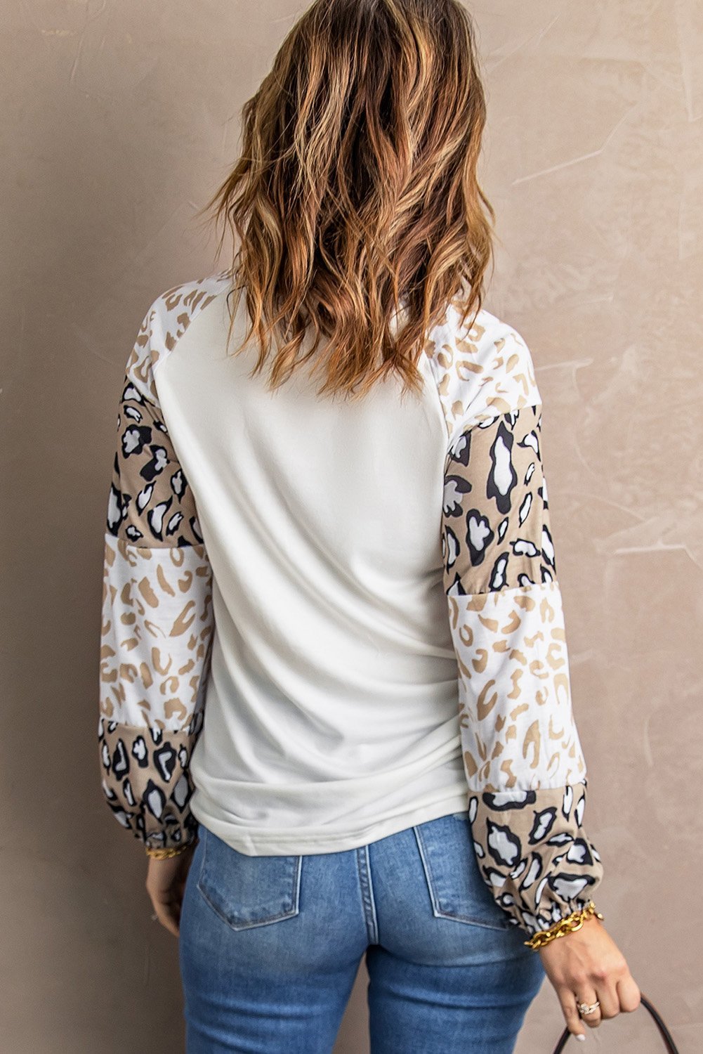 A stylish beige long sleeve top featuring sunflower and leopard prints, designed with bubble sleeves and a loose pullover silhouette.