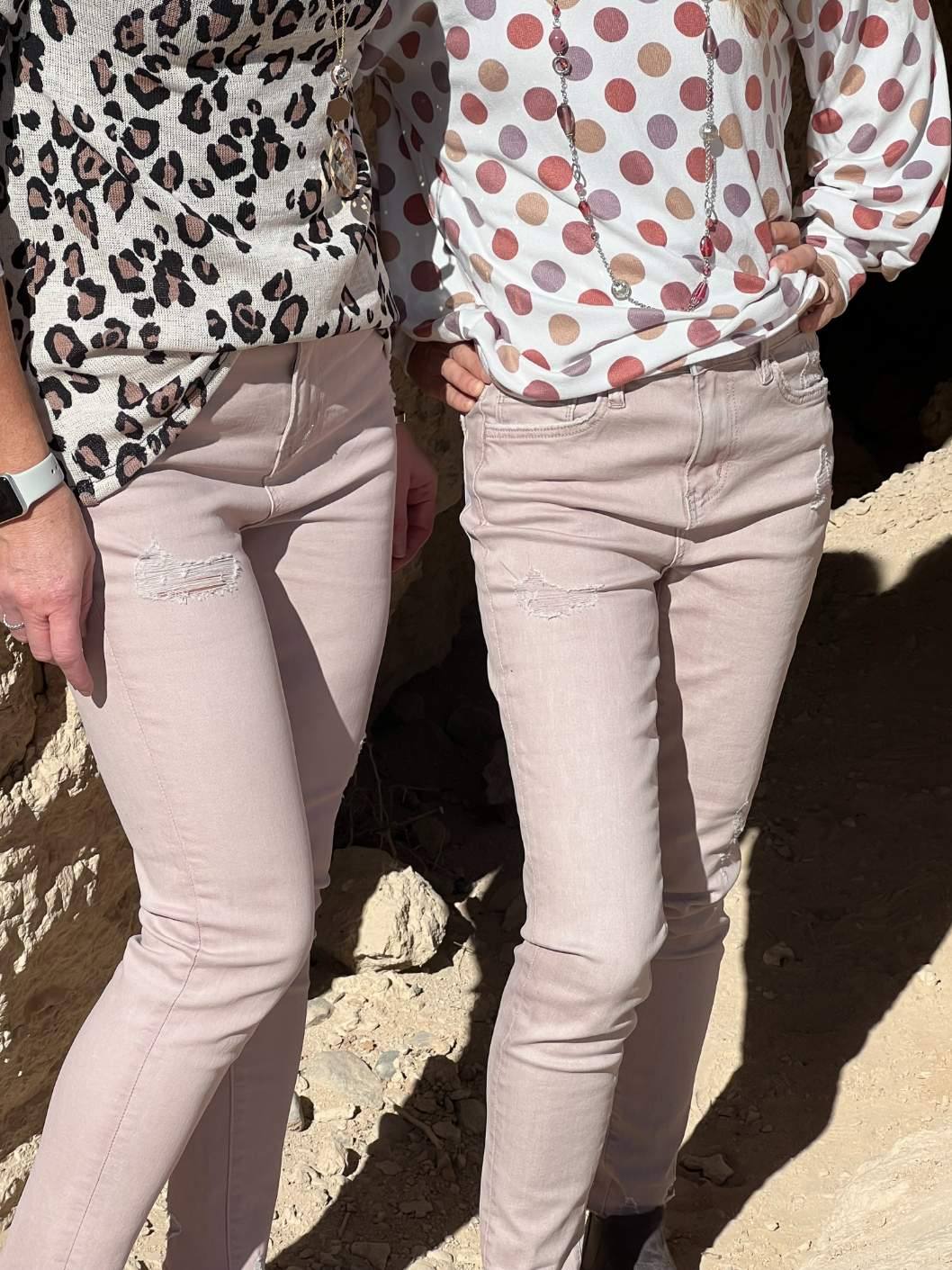 A pair of Vervet Peony Distressed Jeans showcasing a soft peony color with subtle distressing, perfect for spring and summer fashion.