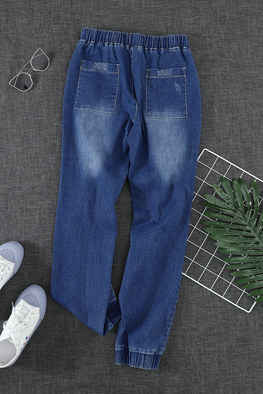 A pair of women's blue pocketed distressed denim joggers featuring an elastic waistband, tapered leg, and stylish ripped details, perfect for casual wear.