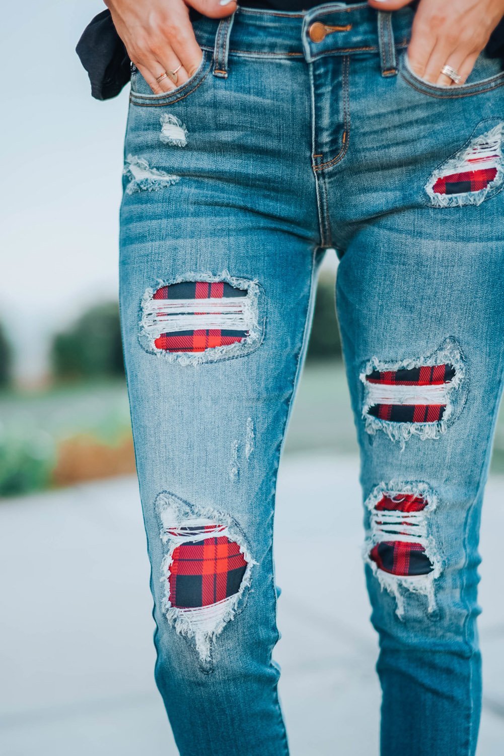 A pair of Women's Fashion Red Plaid Patch Destroyed Skinny Jeans featuring distressed details, plaid patches on the front legs, and a skinny fit silhouette.