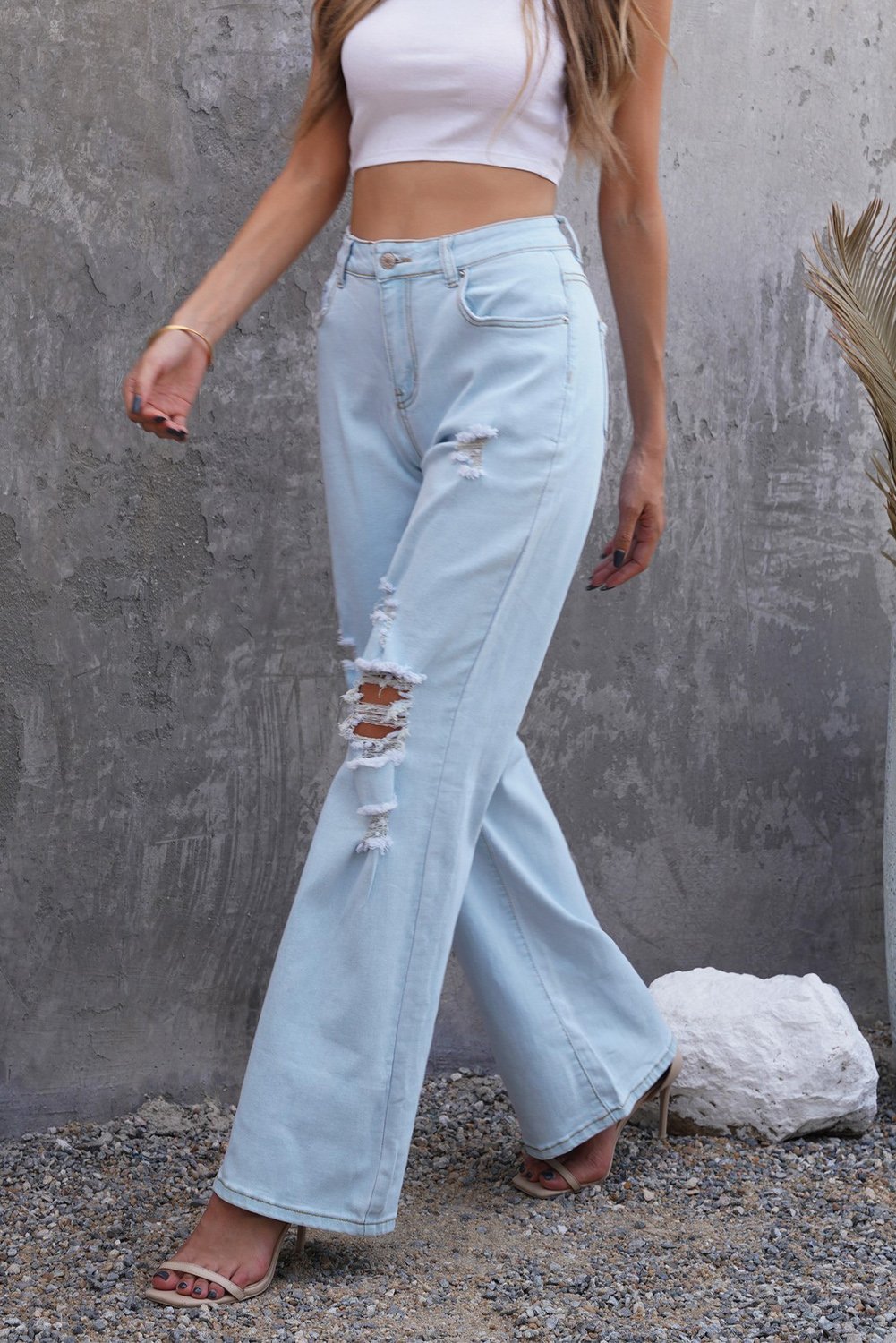 A pair of women's sky blue washed ripped knee wide-leg jeans, featuring a high-rise design and button fly closure, displayed on a white background.