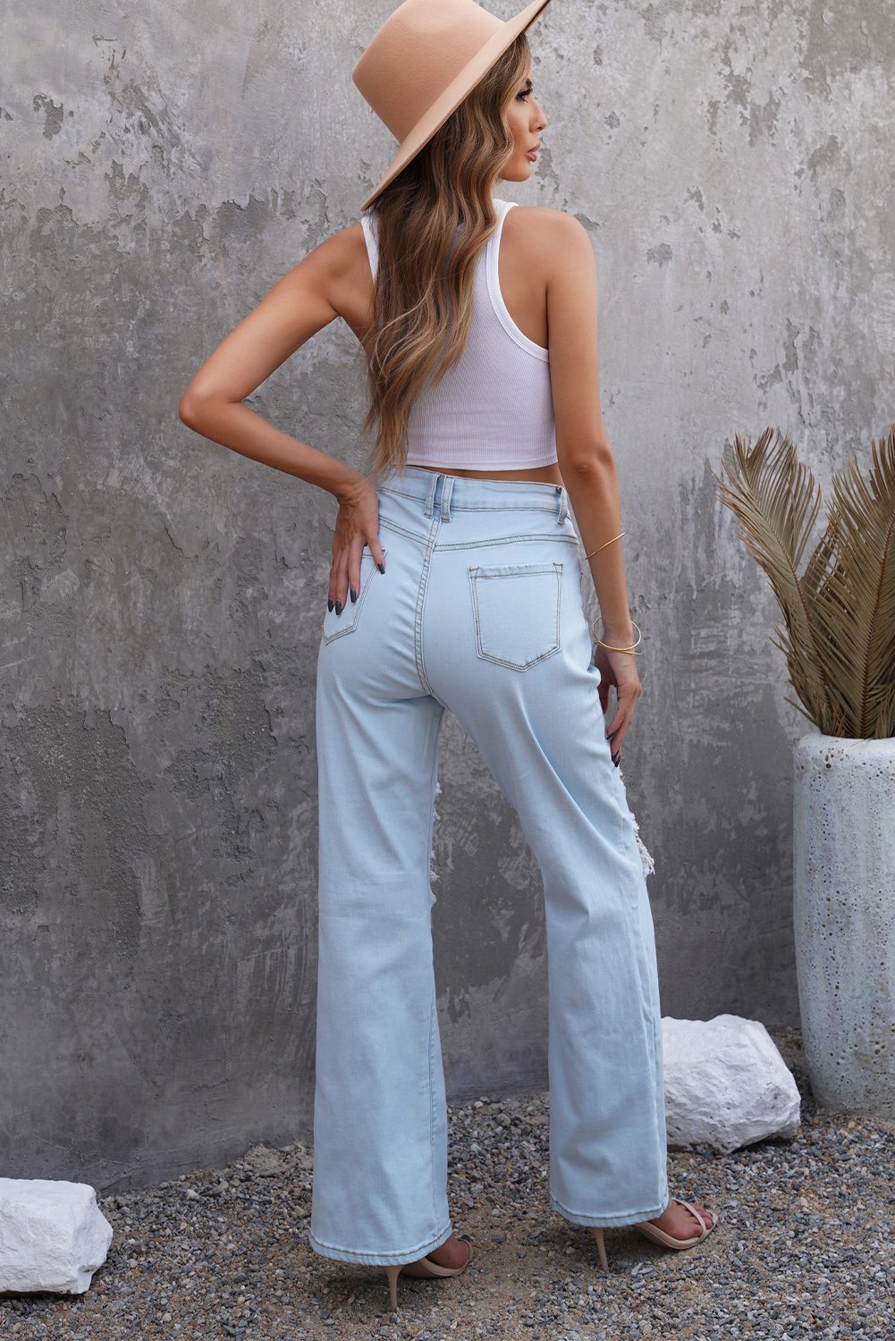 A pair of women's sky blue washed ripped knee wide-leg jeans, featuring a high-rise design and button fly closure, displayed on a white background.