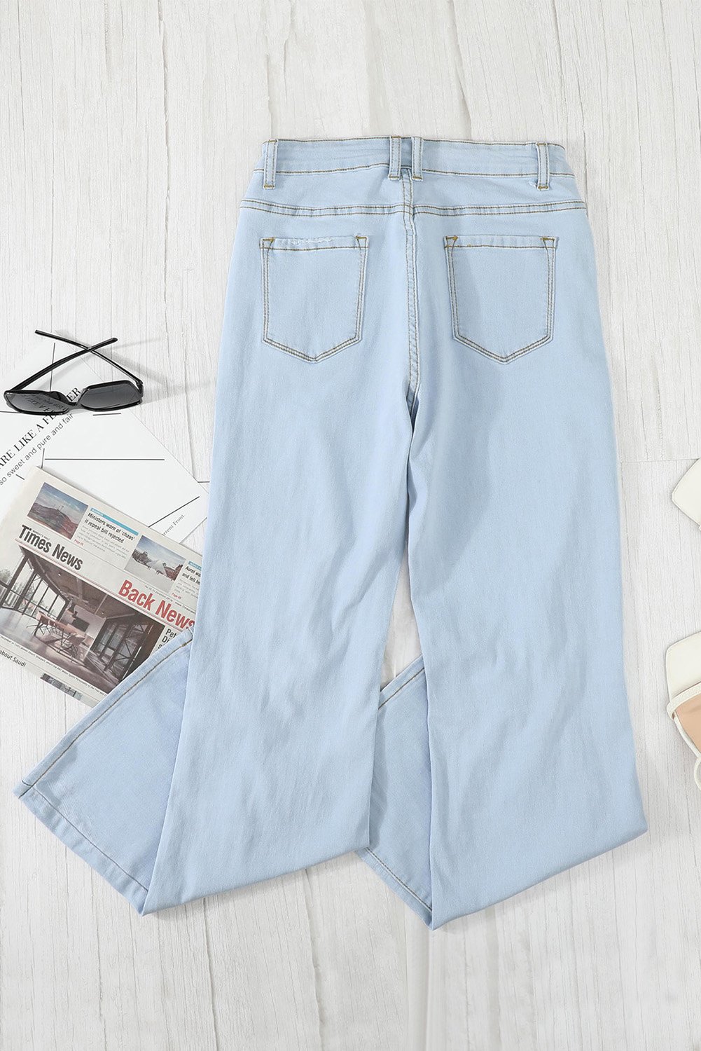 A pair of women's sky blue washed ripped knee wide-leg jeans, featuring a high-rise design and button fly closure, displayed on a white background.