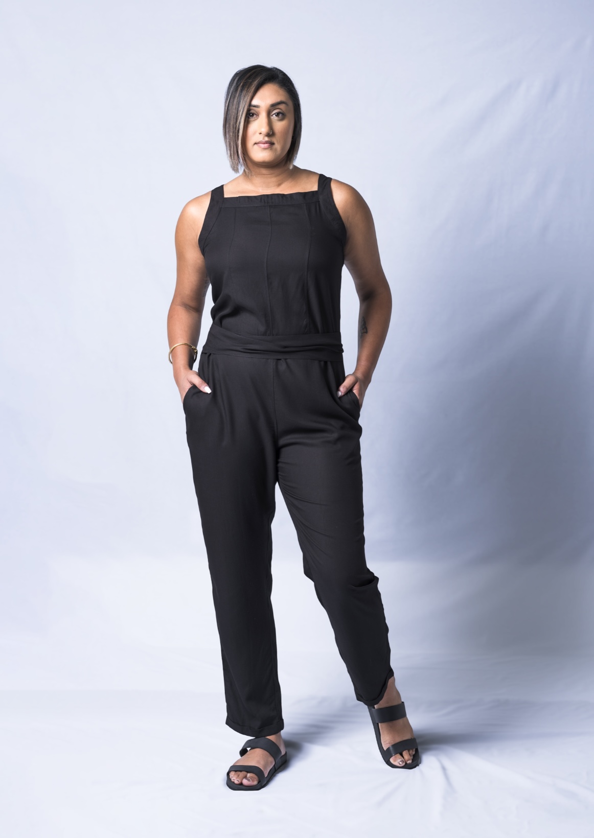 A stylish black jumpsuit featuring a square neck, adjustable waistband, and tapered legs, perfect for various occasions.