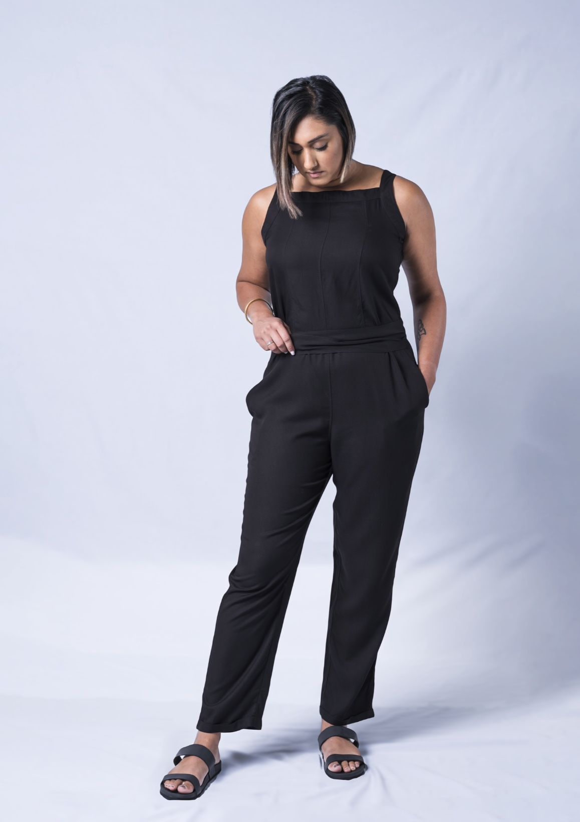 A stylish black jumpsuit featuring a square neck, adjustable waistband, and tapered legs, perfect for various occasions.