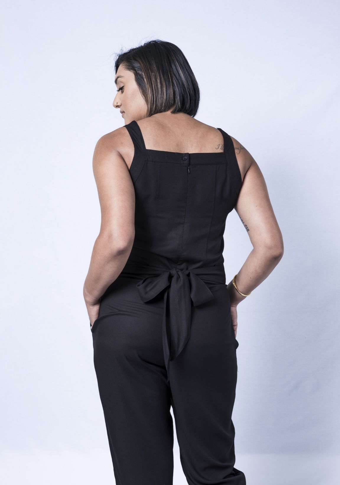 A stylish black jumpsuit featuring a square neck, adjustable waistband, and tapered legs, perfect for various occasions.