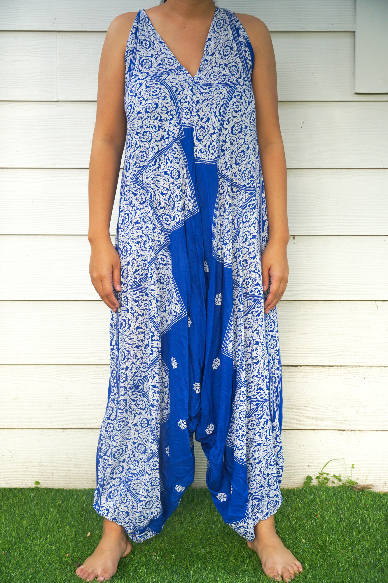 A vibrant blue floral hippie jumpsuit with wide legs, adjustable straps, and elasticated back, perfect for summer festivals and beach wear.