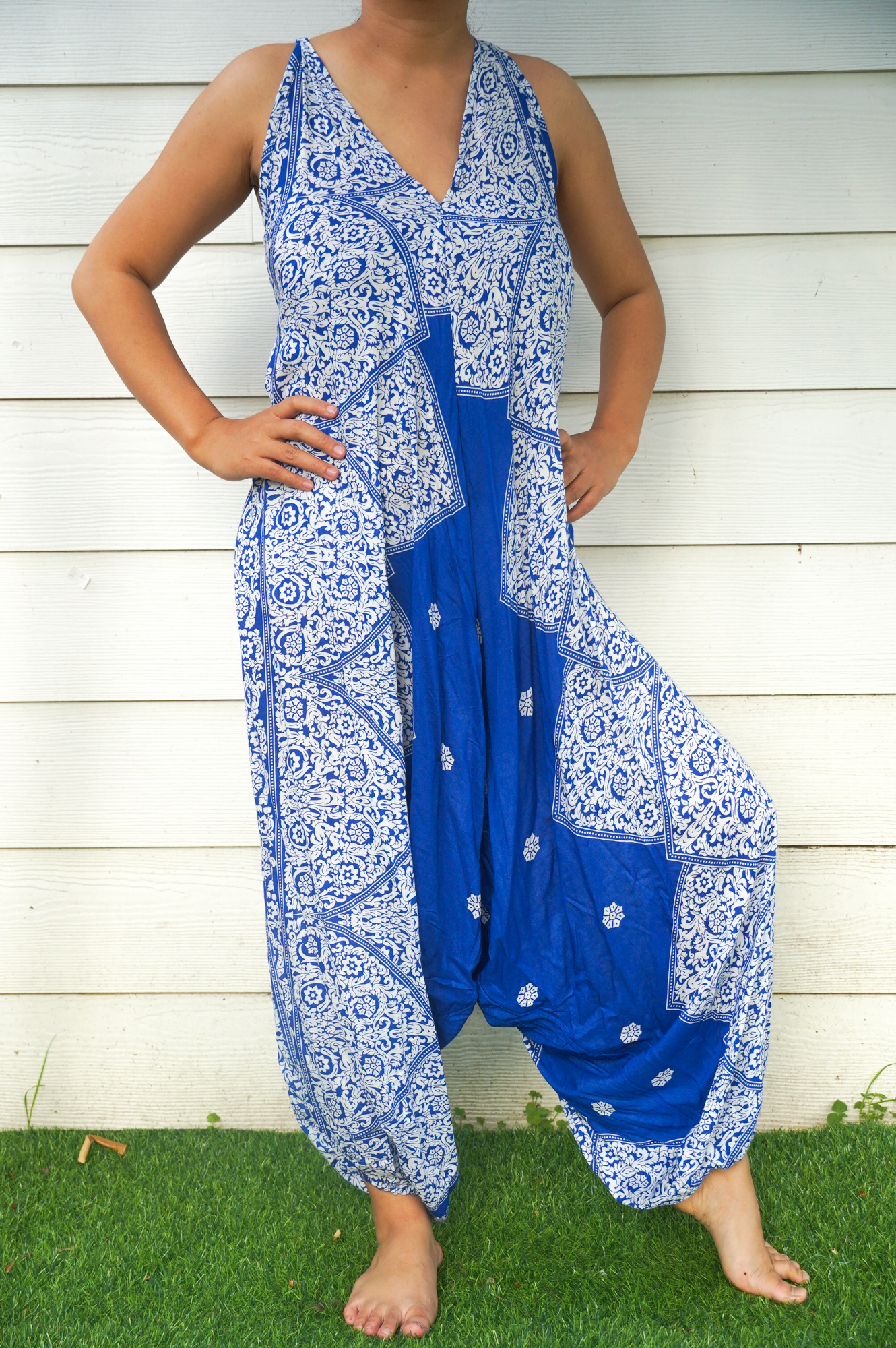 A vibrant blue floral hippie jumpsuit with wide legs, adjustable straps, and elasticated back, perfect for summer festivals and beach wear.