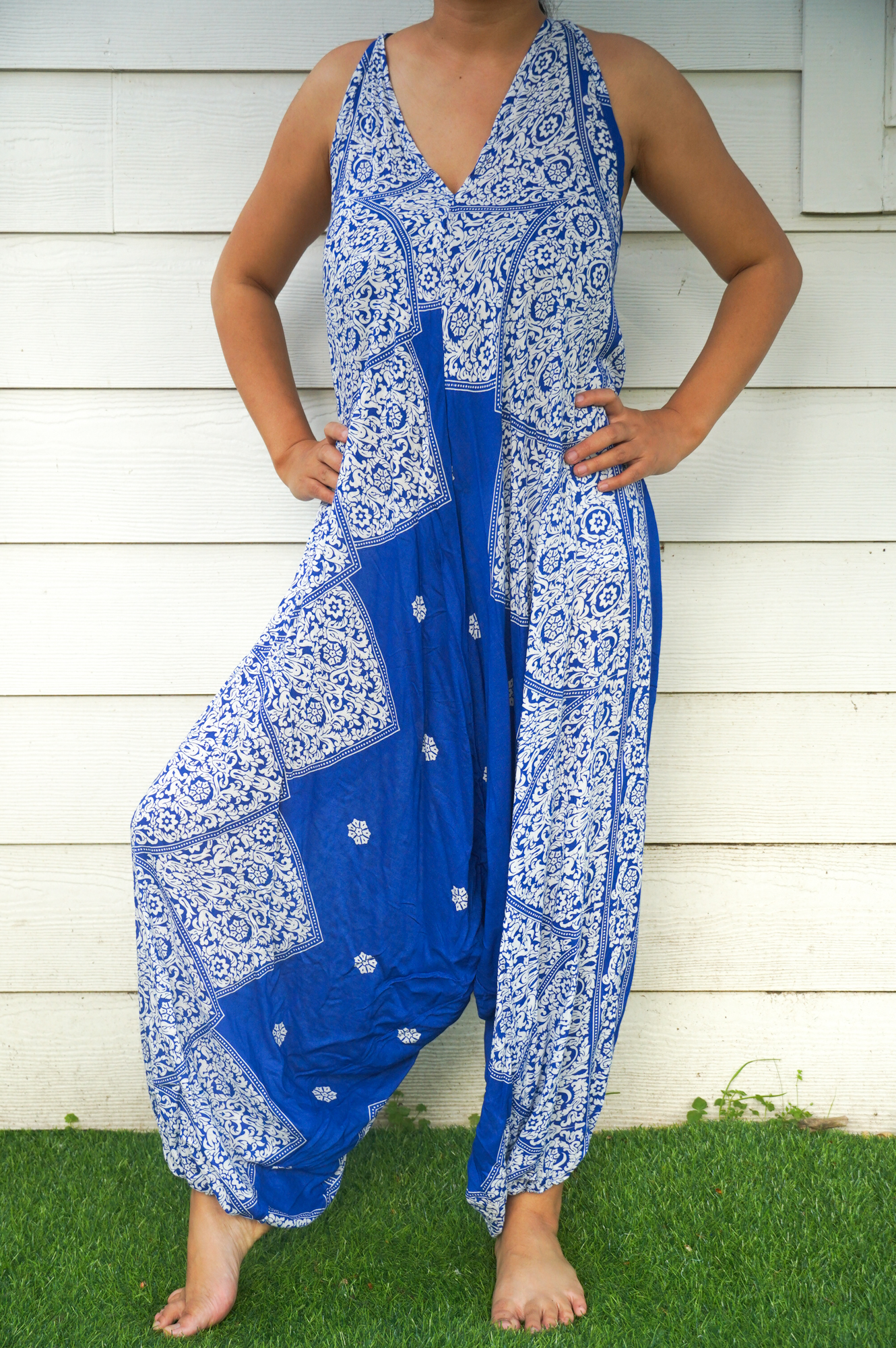 A vibrant blue floral hippie jumpsuit with wide legs, adjustable straps, and elasticated back, perfect for summer festivals and beach wear.