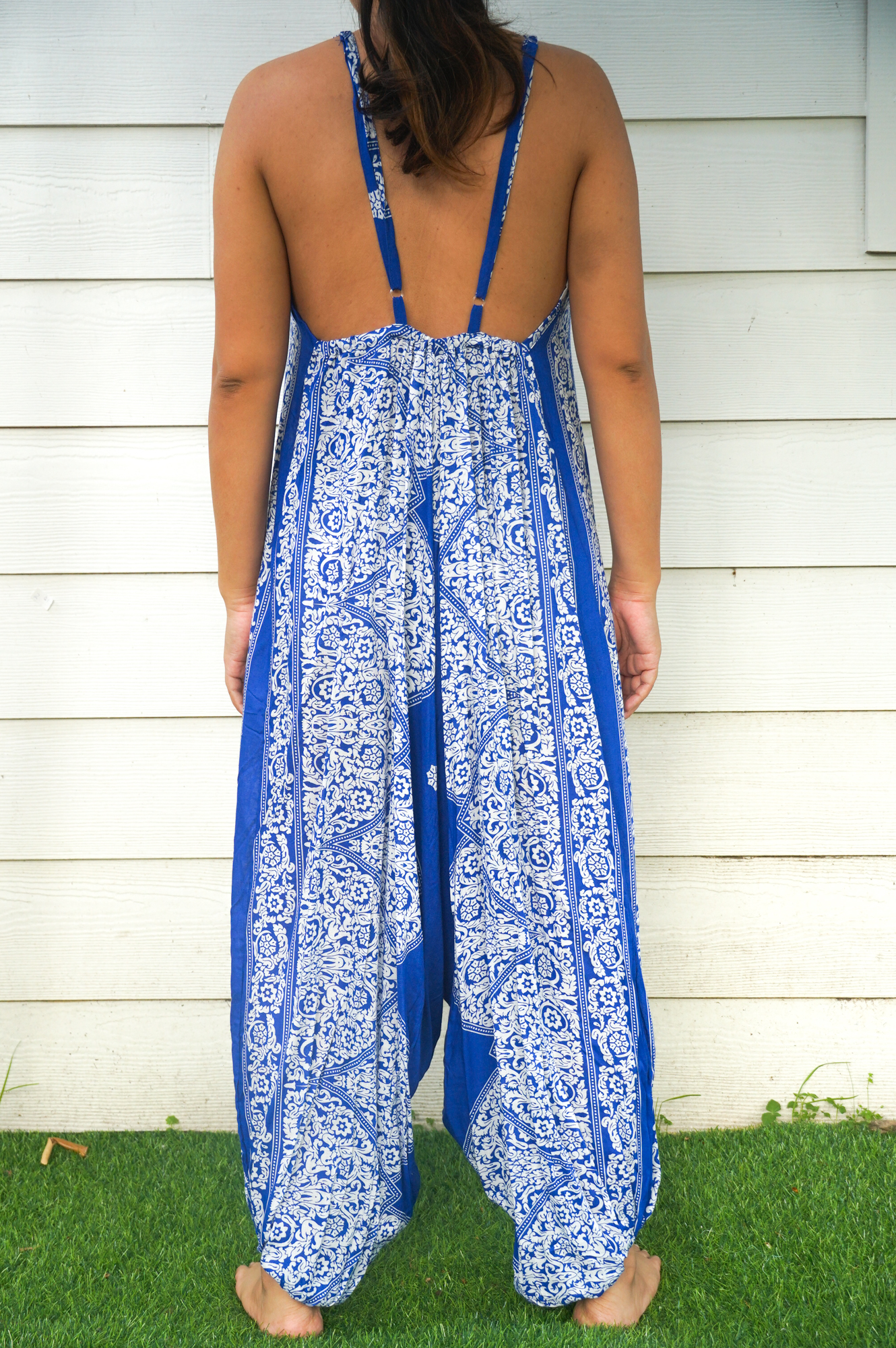 A vibrant blue floral hippie jumpsuit with wide legs, adjustable straps, and elasticated back, perfect for summer festivals and beach wear.