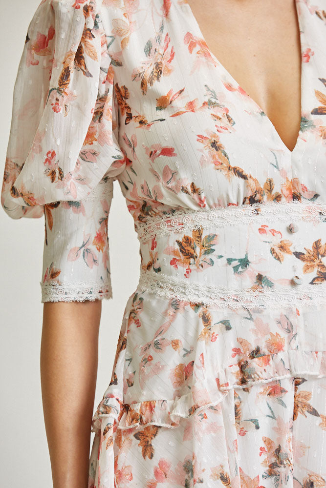 The Doana romper featuring a floral print, V-neckline, puff shoulder sleeves, and lace details, perfect for stylish summer outings.