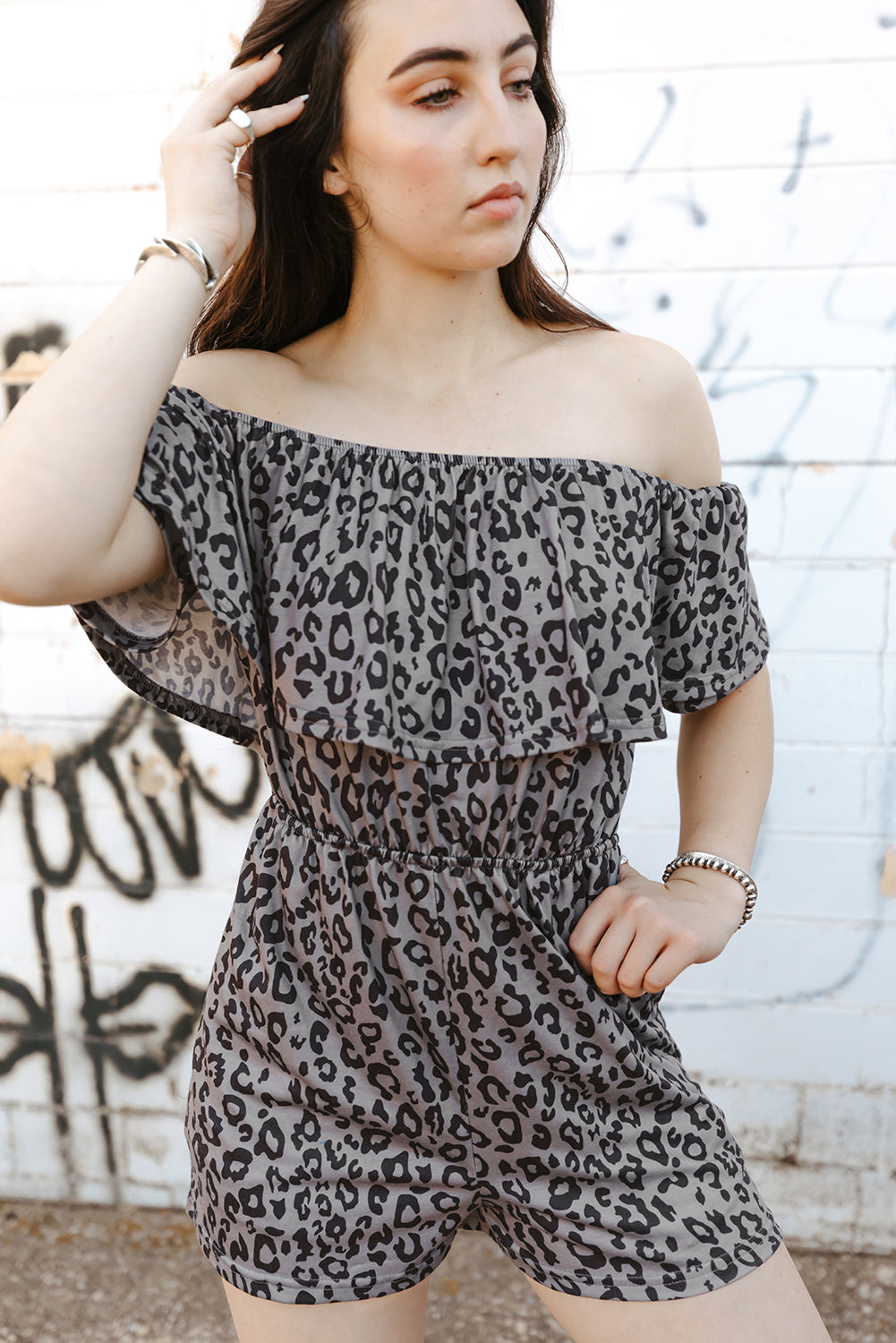 A stylish leopard print off-shoulder romper with pockets, displayed in a flat lay outdoors, showcasing its casual and chic design.