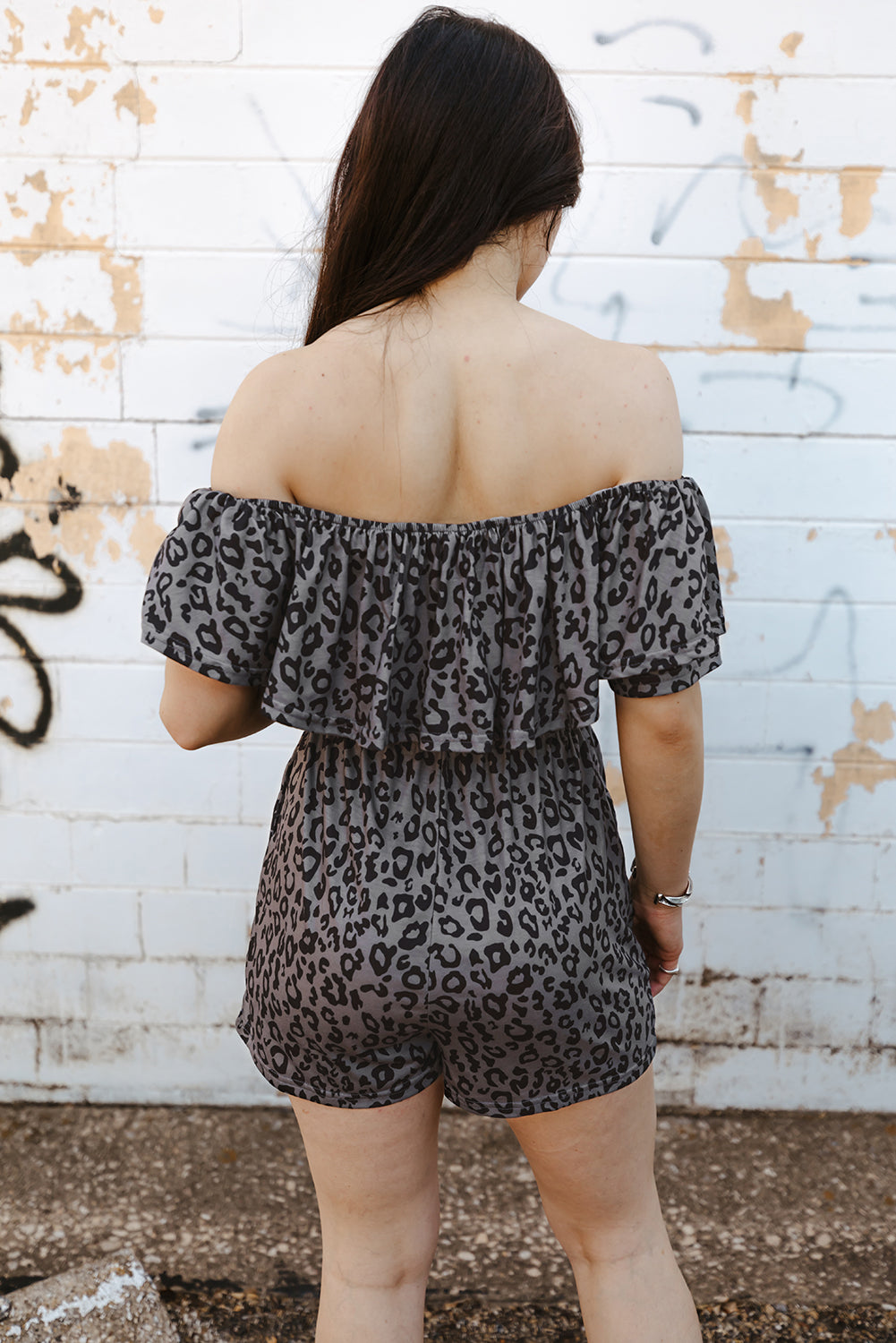 A stylish leopard print off-shoulder romper with pockets, displayed in a flat lay outdoors, showcasing its casual and chic design.