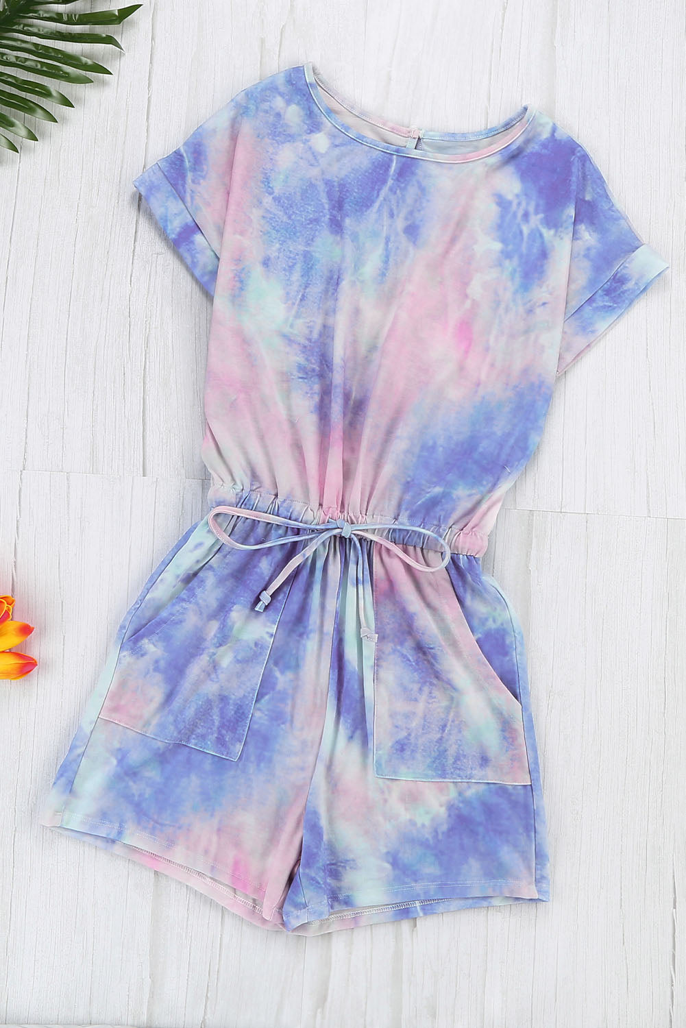 Multicolor Pocketed Tie Dye Short Sleeve Knit Romper featuring a vibrant tie-dye pattern, short sleeves, and an elastic drawstring waist for a comfortable fit.