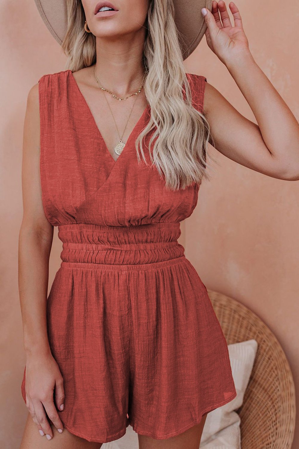 A stylish red smocked pocketed sleeveless v-neck romper, featuring a draped neckline and high-waisted shorts, perfect for summer outings.