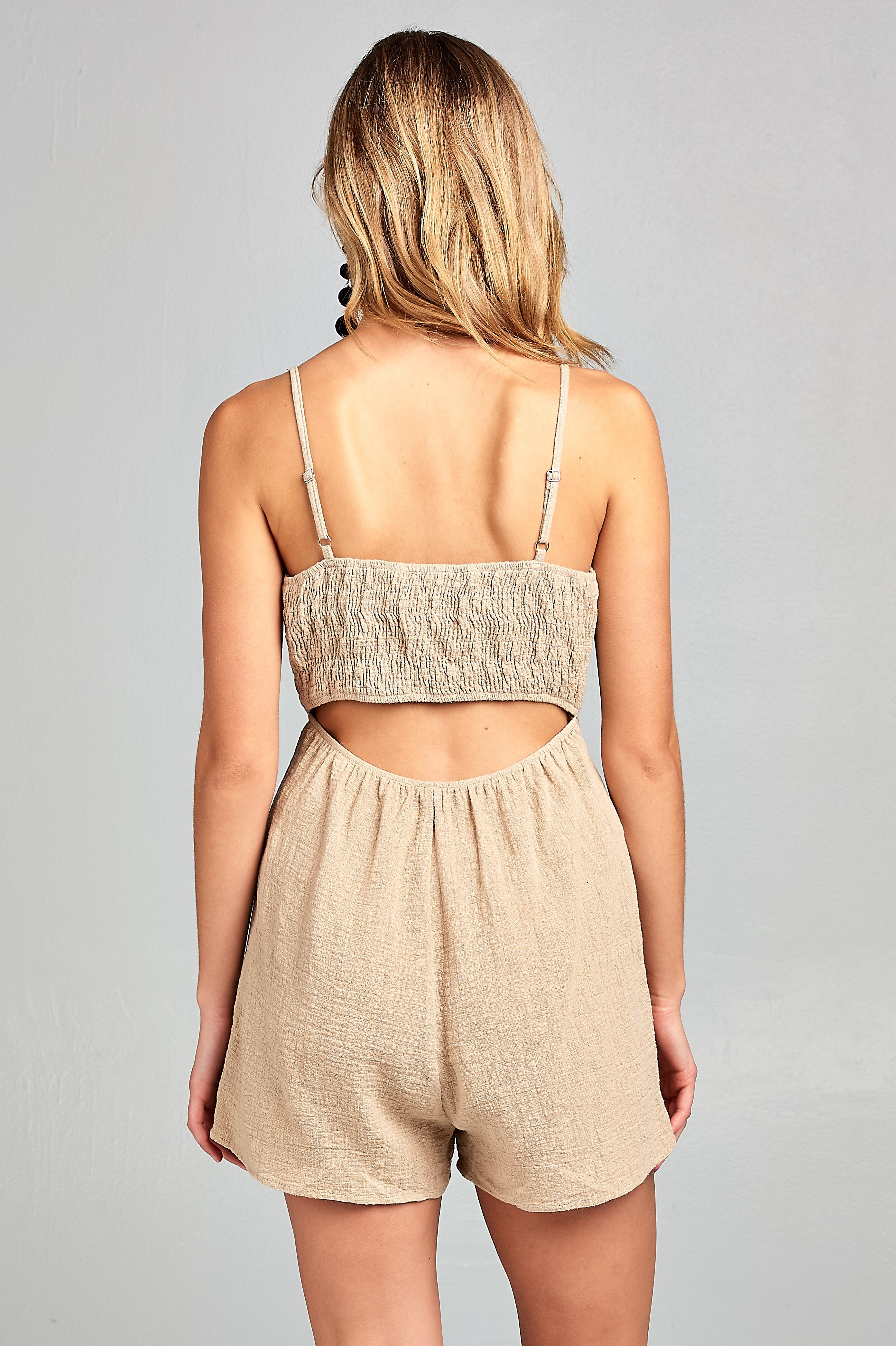 Woman in beige romper, back view.