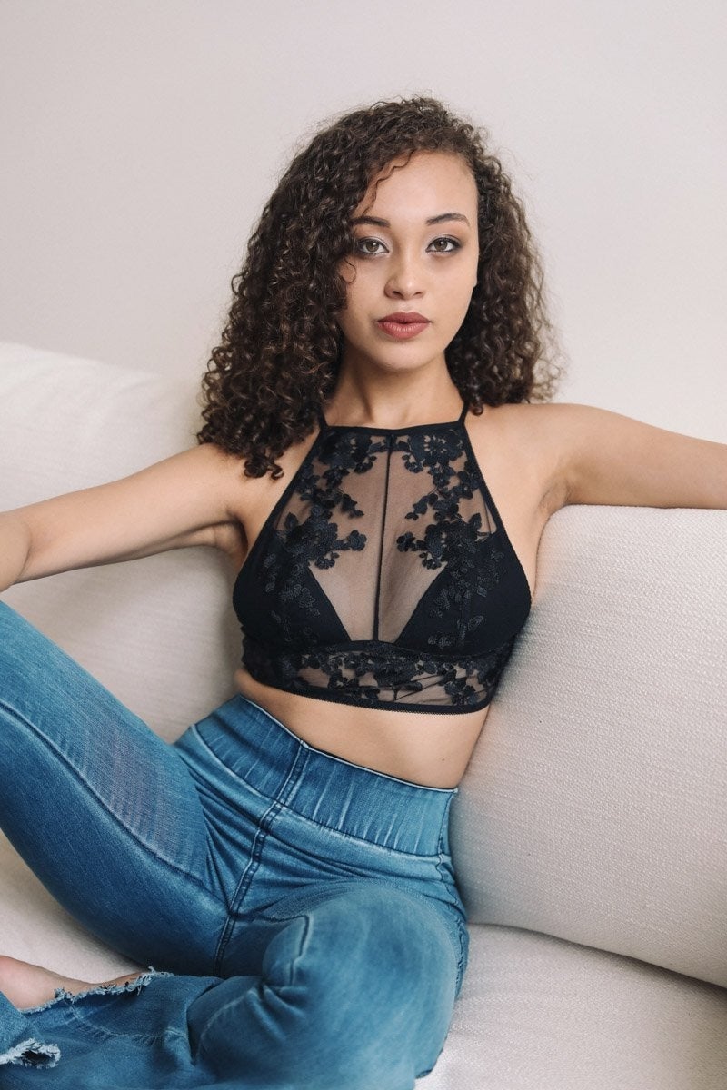 A sheer lace high neck bralette featuring intricate floral embroidery, showcasing elegance and whimsy.